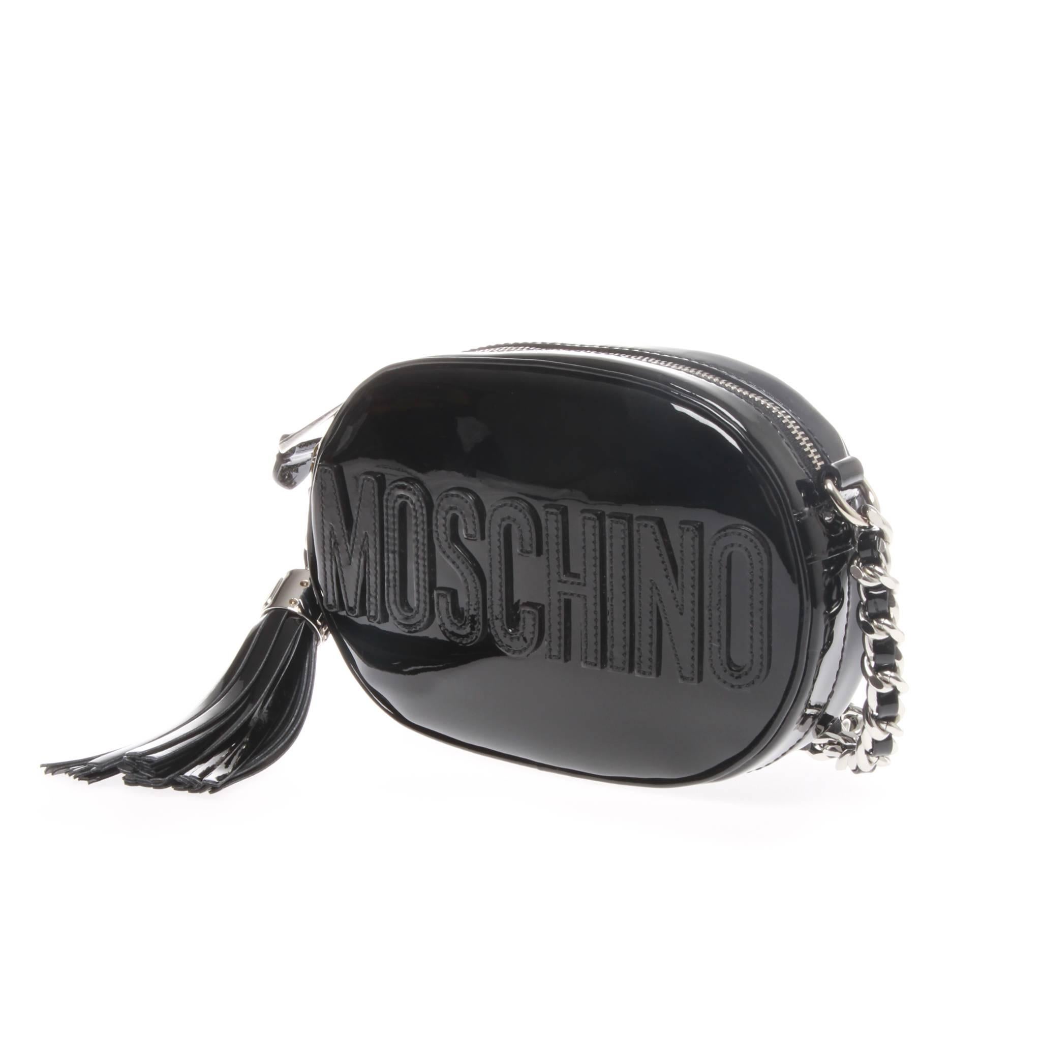 Moschino oval logo cross-body bag in black patent leather. MOSCHINO applique to front side is the bags main design feature, as well as a removable tassel bag charm in matching red patent leather that is also threaded through the chain shoulder