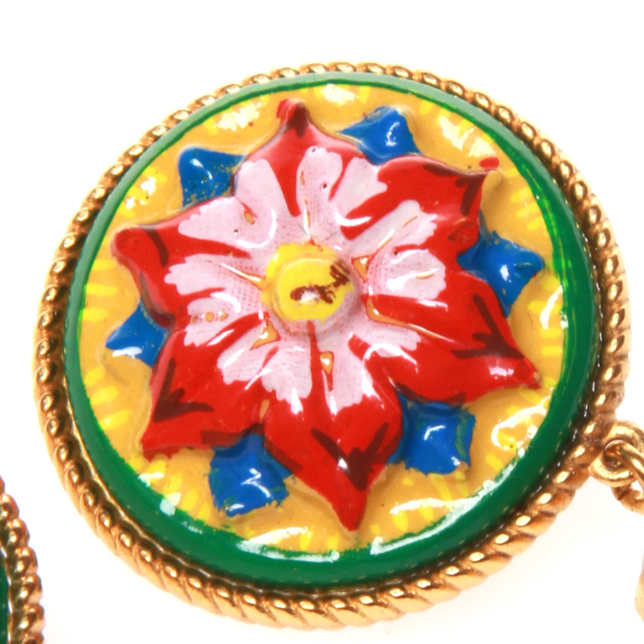 Dolce and Gabbana clip on earrings with an intricately metal-worked gold-tone base and multicoloured lacquer flower design featuring a red cut glass gemstone. Clip-on fastening. 

New with tags and comes with all original packaging.  