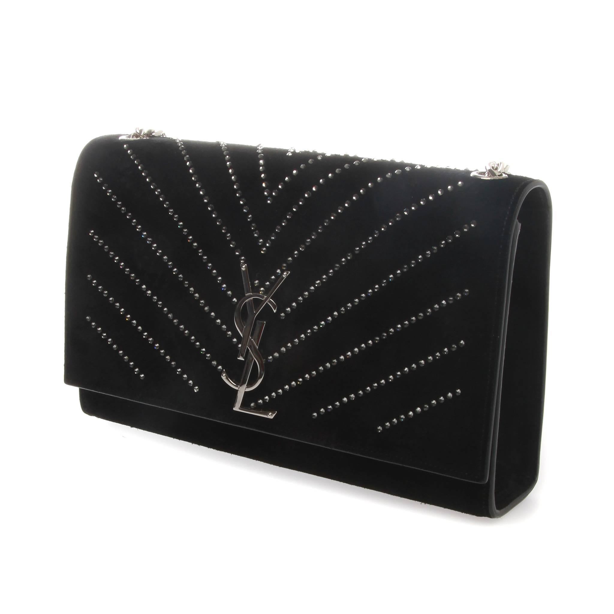 Saint Laurent classic monogram Kate crossbody bag in nero black and embellished with diamante darting.
This elegant evening clutch is crafted of suede leather in black. The bag features crystals covering the flap and rear, a polished silver bijoux