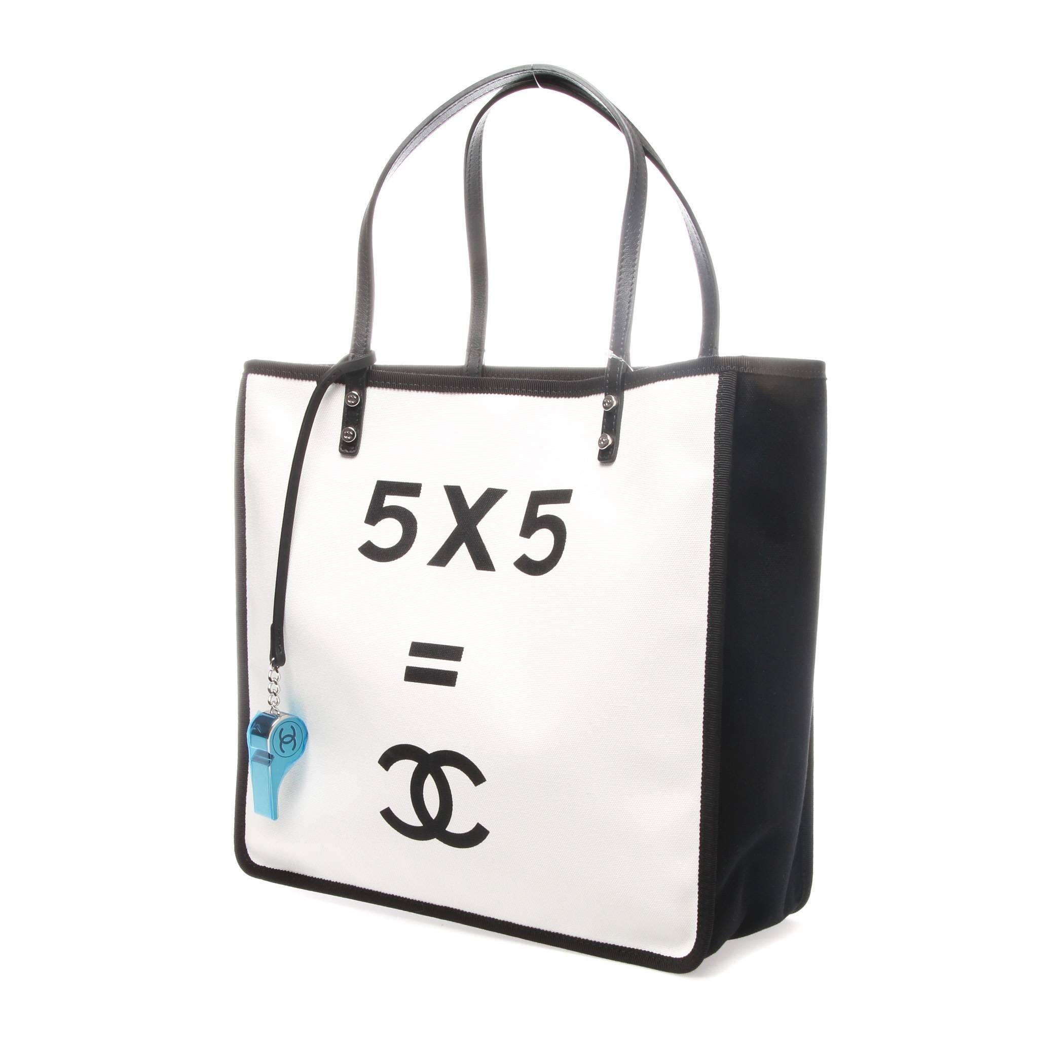 Black and white canvas Chanel 5X5 tote with silver-tone hardware, black leather trim, dual flat shoulder straps, silver-tone whistle charm embellishment at front face, burgundy quilted canvas lining, dual pockets at interior walls with snap closures