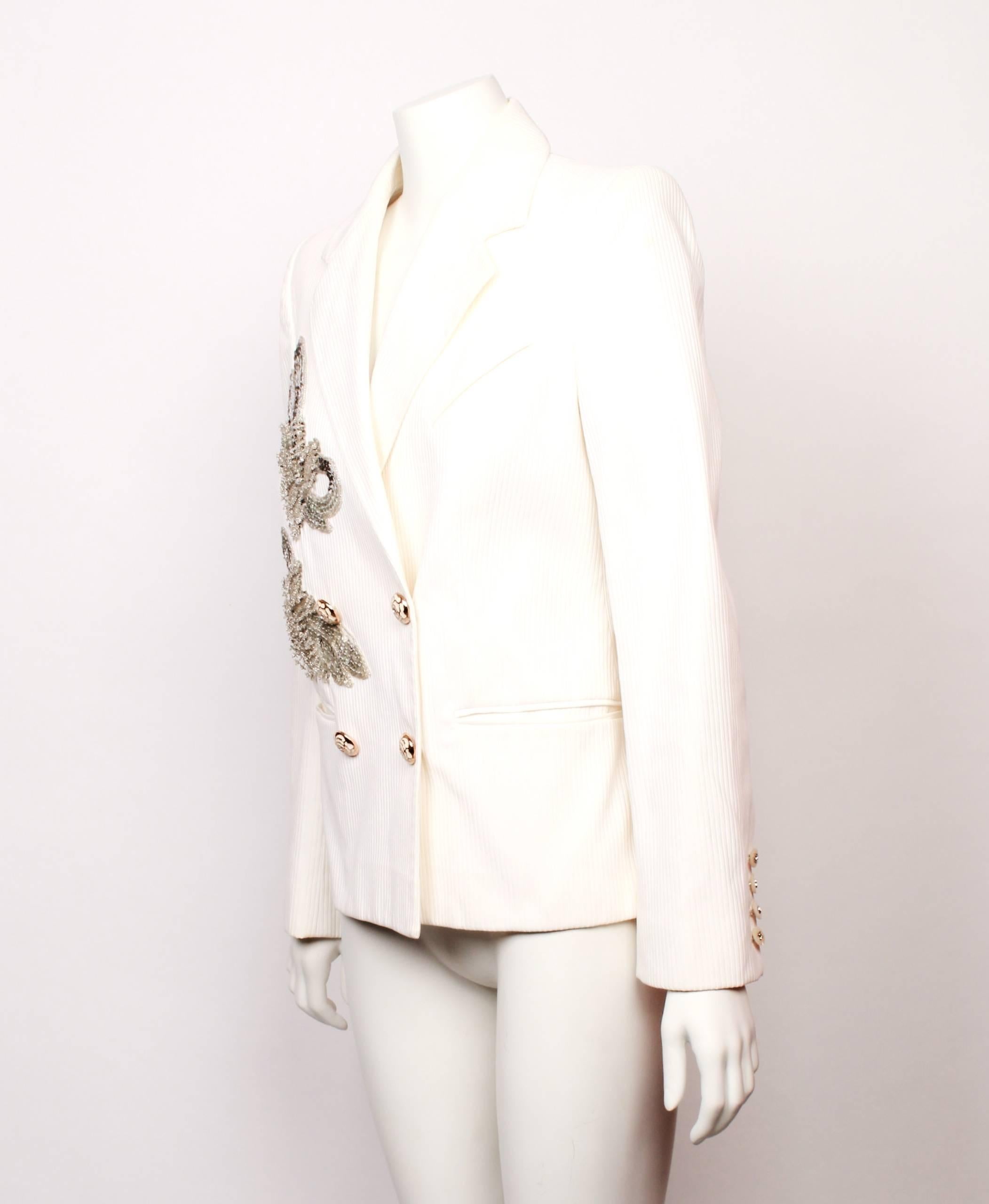Chanel white faille ribbed jacket with two silver sequin leaf shaped motifs. Double breasted with beautiful and classic Chanel Camelia buttons in gold and white.
The jacket features two welt pockets at the hip and one breast pocket placed on the