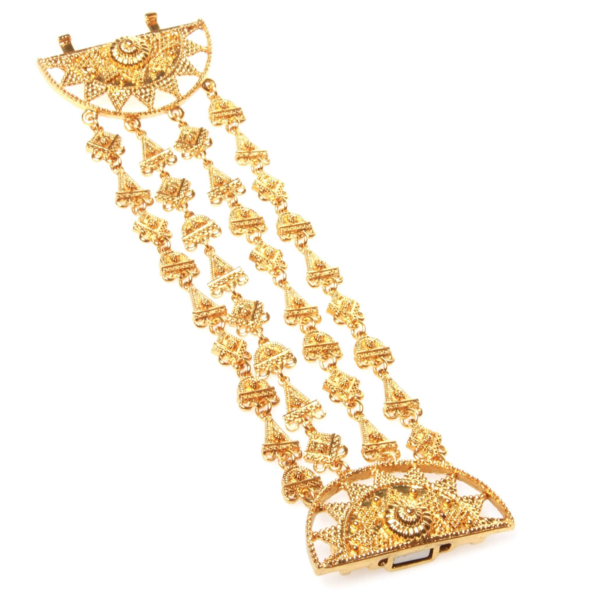 Beautiful Oscar De La Renta multi-strand bracelet in a lustrous gold-tone metal featuring strands of intricate metal work strung between a magnetic closure circular centrepiece. 

Comes with original pouch and box. 