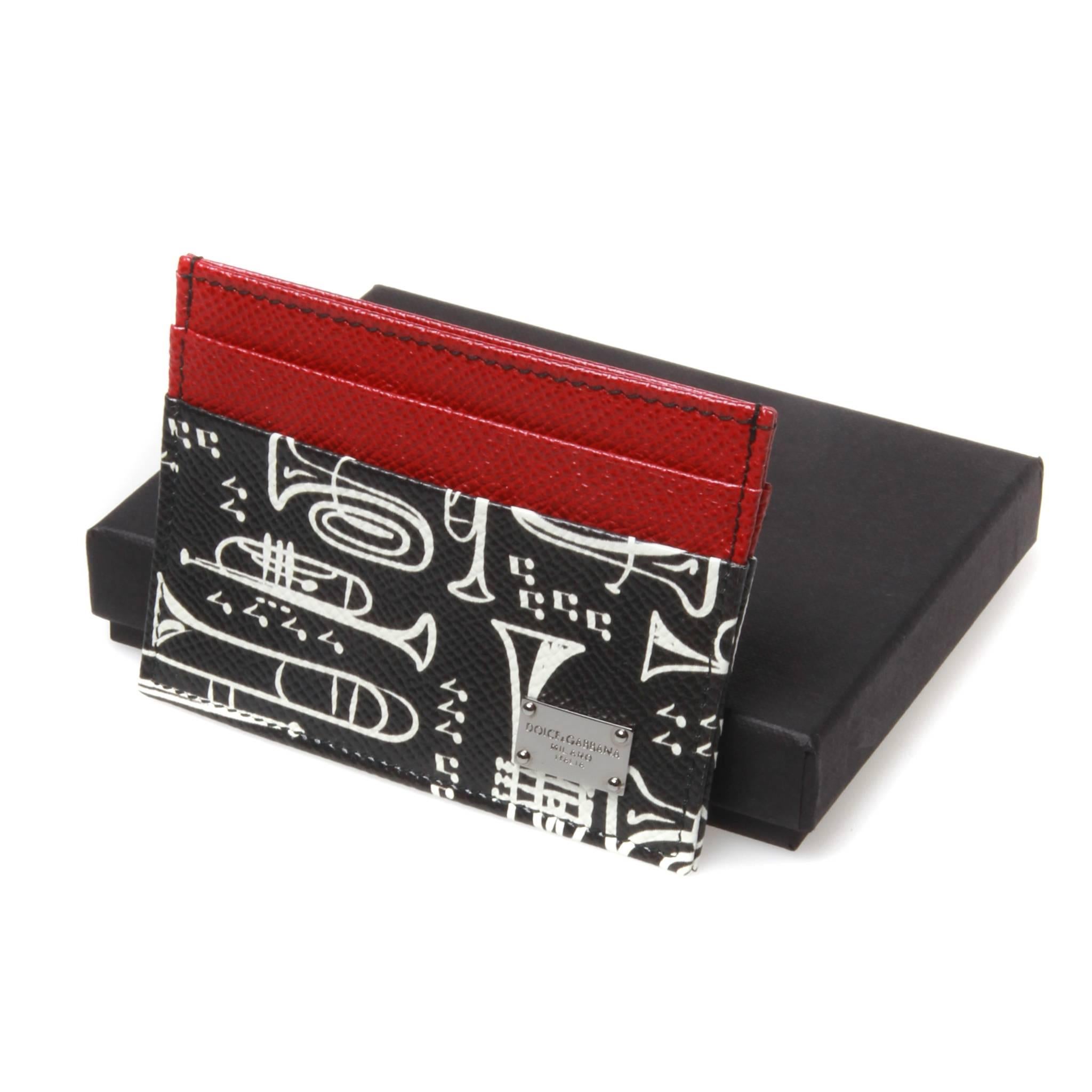 Final Sale

Dolce and Gabbana grain calf leather card holder featuring a black and white musical instrument graphic and red contrast panels. Two card slots and one central slip for notes and receipts. Silver-tone plaque affixed to front side. 