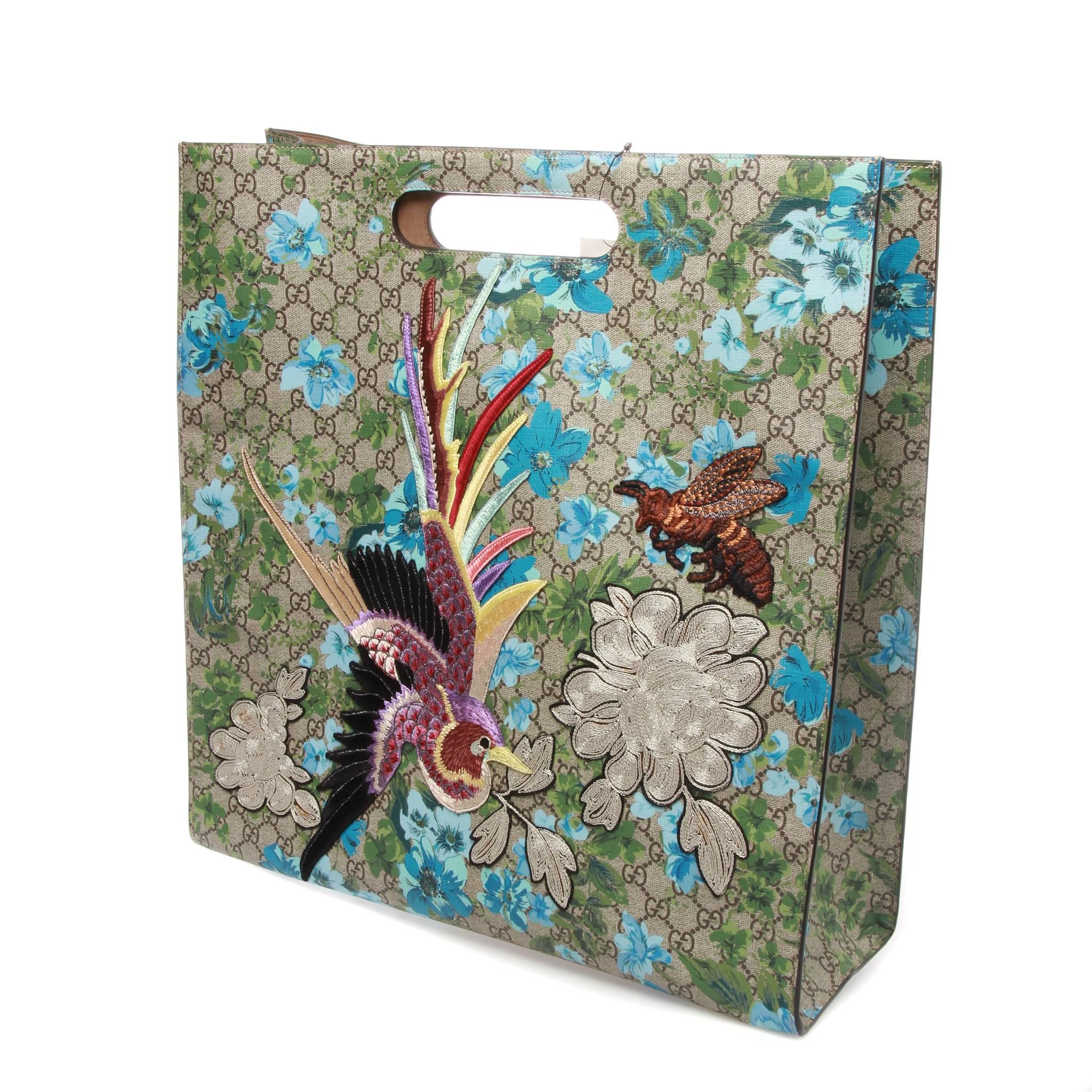 Unisex ebony and beige GG Supreme coated canvas Gucci XL GG Floral Print tote with dual cut-out handles, blue and green GG Blooms motif throughout, multicolor embroidered fauna embellishment at front face, tawny suede interior and open top.

Serial