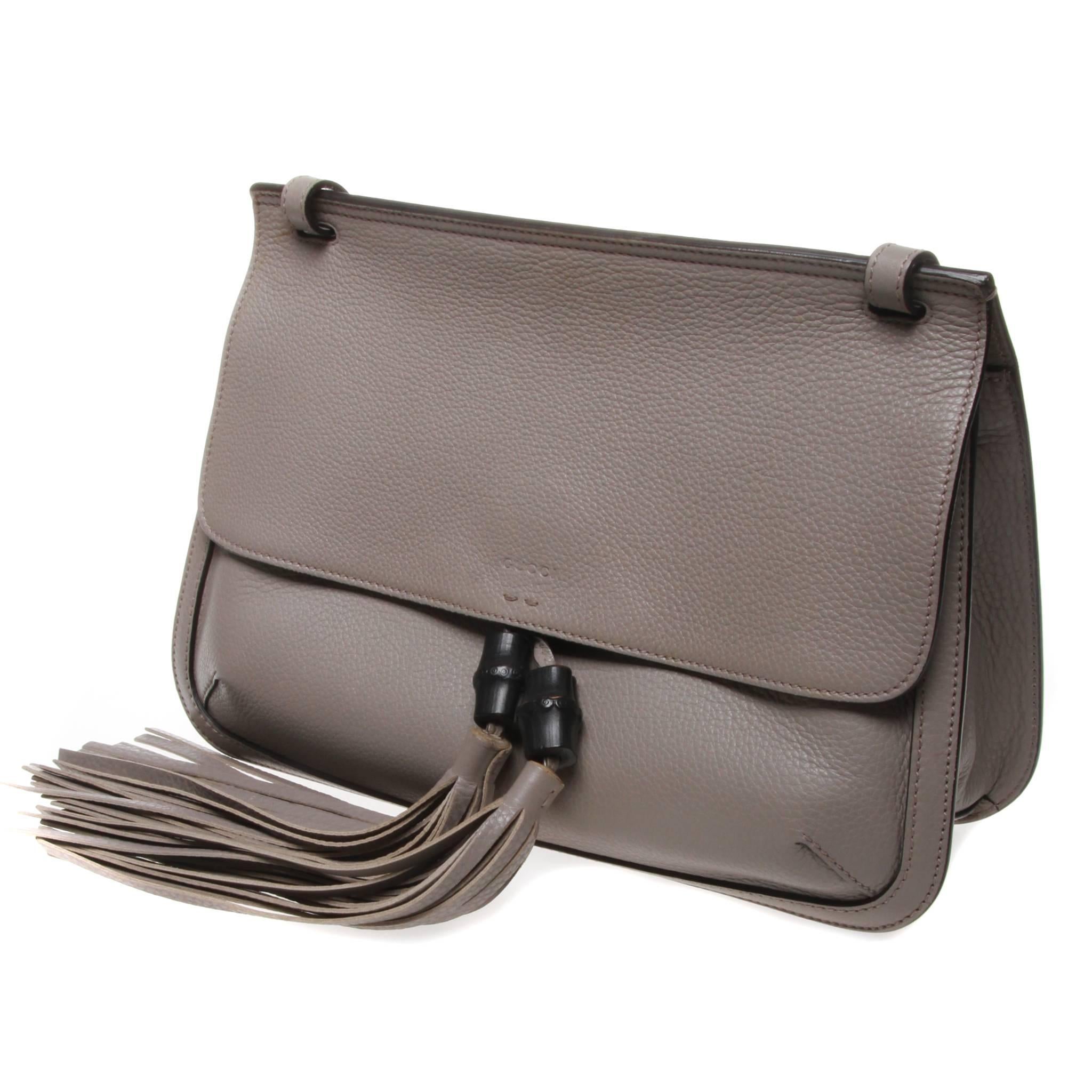 Gucci Bamboo Daily leather flap shoulder bag in light grey. This bag features a main compartment with two open pockets and one zip pocket sewn into the tone-on-tone baiadera cotton-linen lining, an open front pocket outside the main compartment and