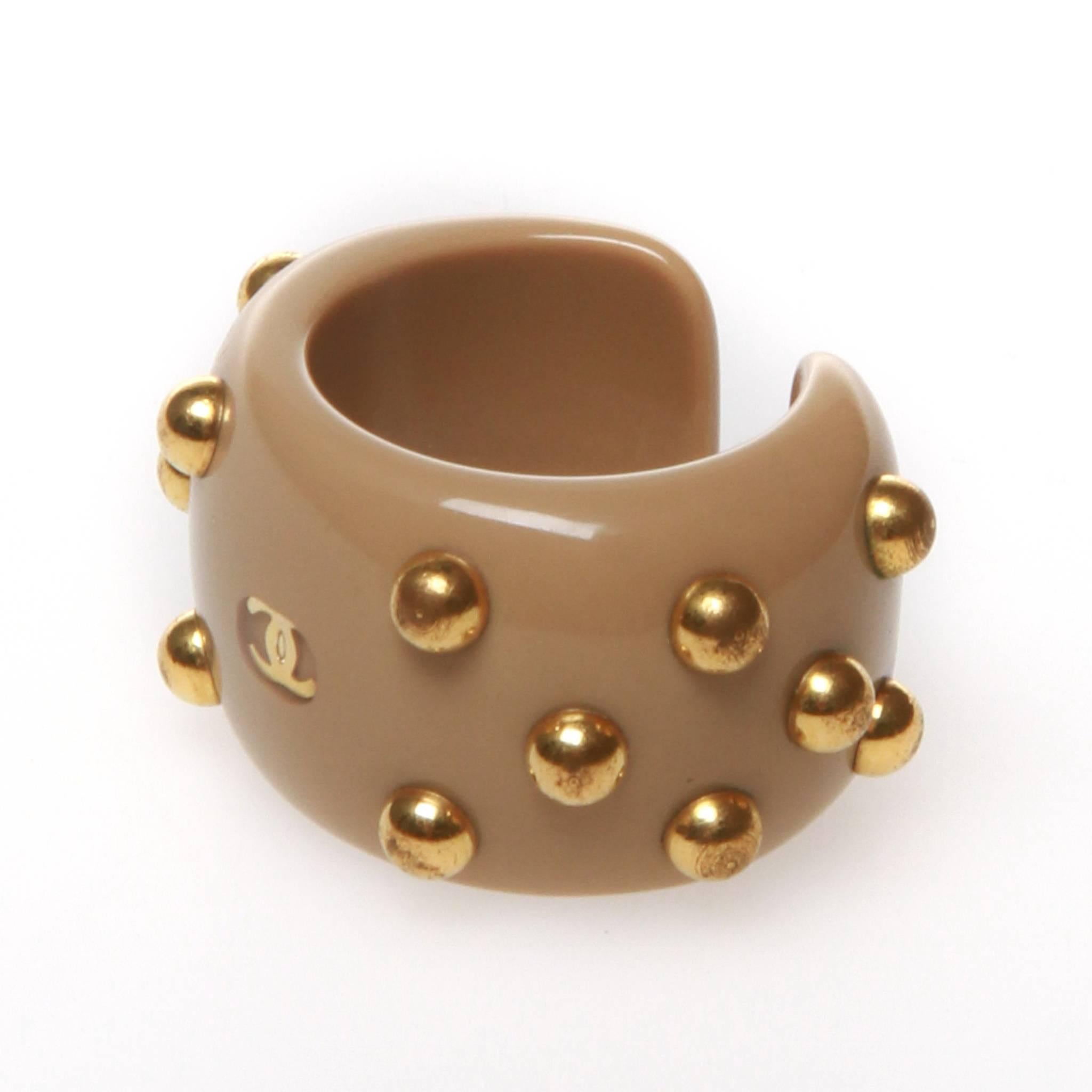 Chanel ring in beige resin with gold-tone metal studs throughout and central interlocking CC. 

Size M. 