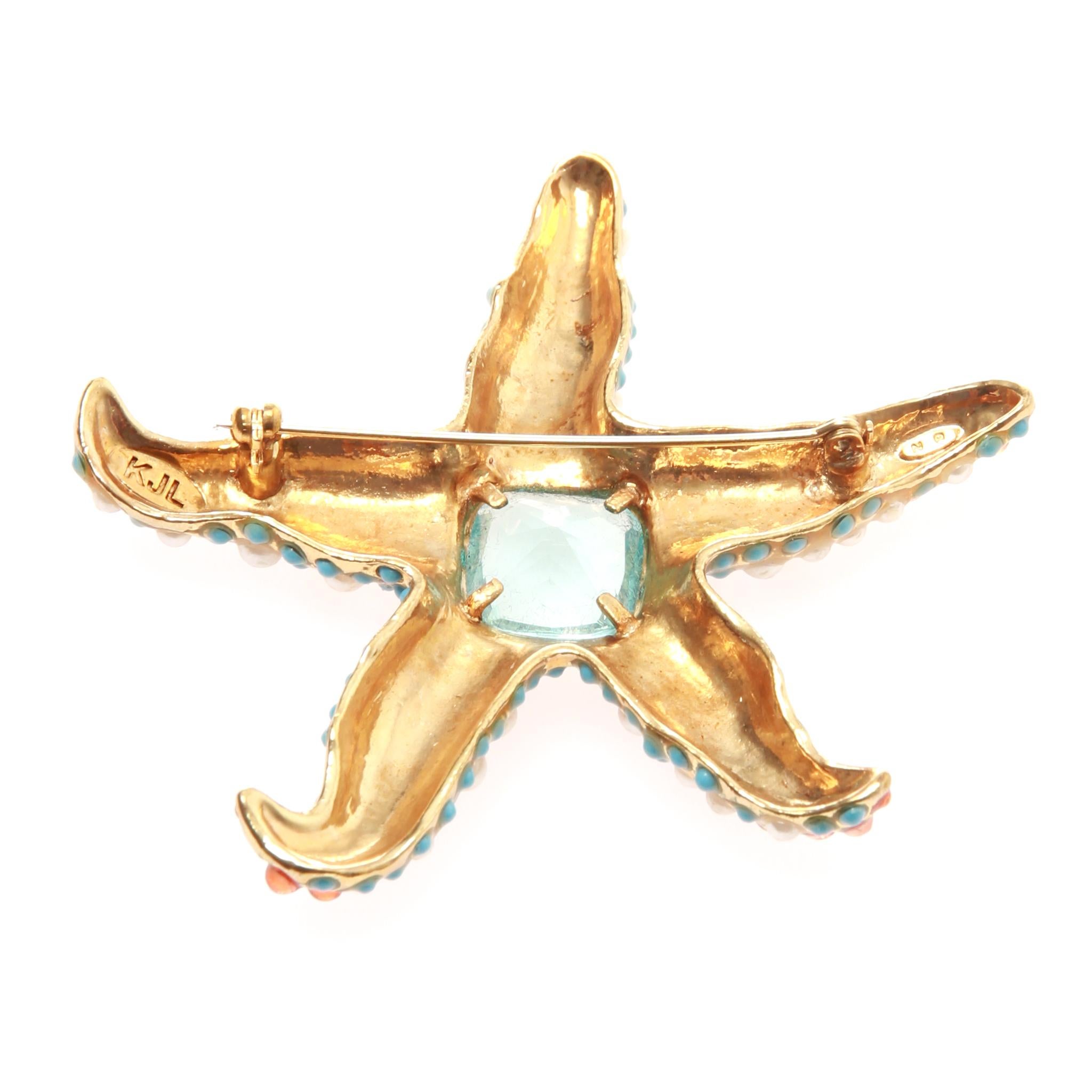 KENNETH JAY LANE Starfish Brooch
It features turquoise and coral colored plastic stones as well as faux pearls. 
The center stone is a faceted aqua blue glass stone which is surrounded by clear crystals. 
A gorgeous piece of the sea to embellish