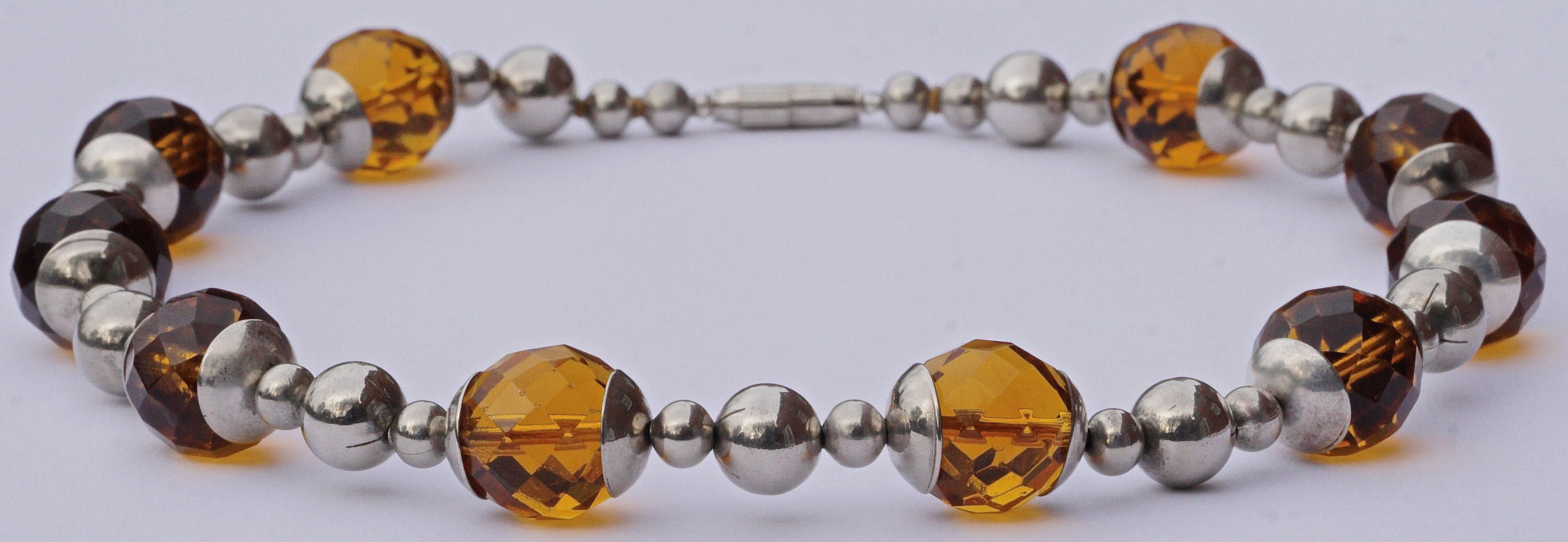 Art Deco chrome necklace featuring faceted amber glass beads, length 46.7cm / 18.4 inches. The glass beads are diameter 1.5cm / .59 inch. This necklace has been professionally restrung, and the vintage barrel clasp is a replacement.

The contrasting