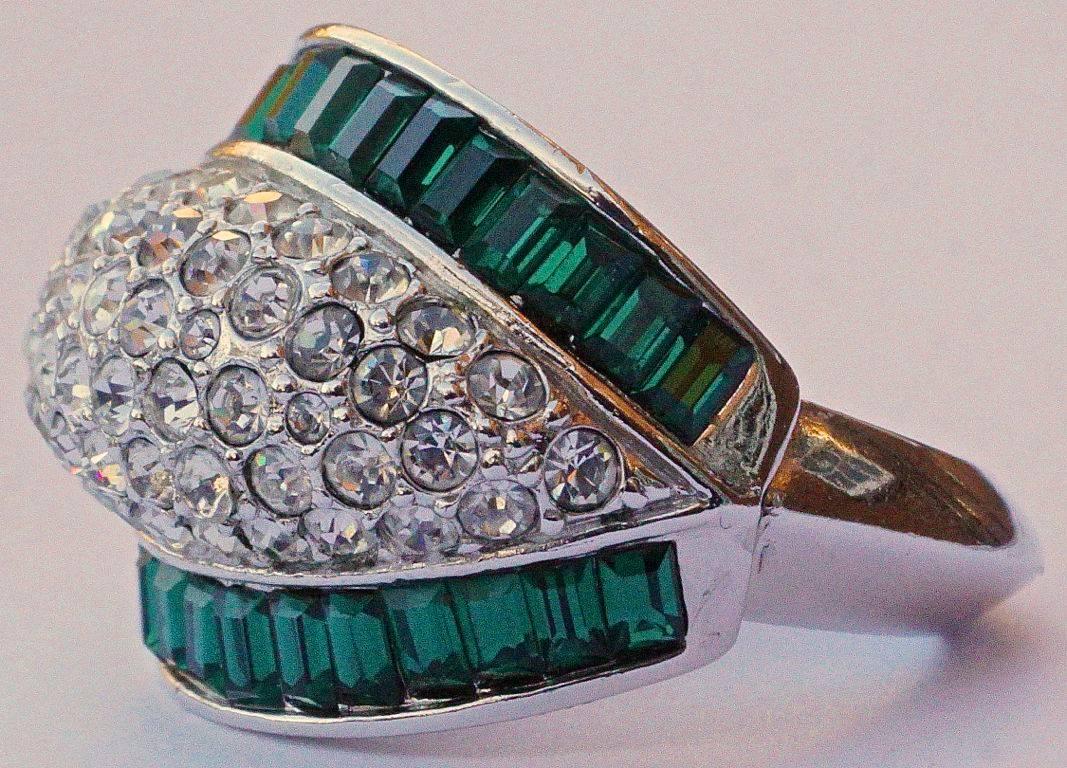 Silver tone bombé cocktail ring designed with two rows of green baguette rhinestones, edging clusters of clear rhinestones. Ring size UK K, US 5 1/4  (inside diameter 1.7cm), but will adjust to fit a smaller size with the integral sizer. It is