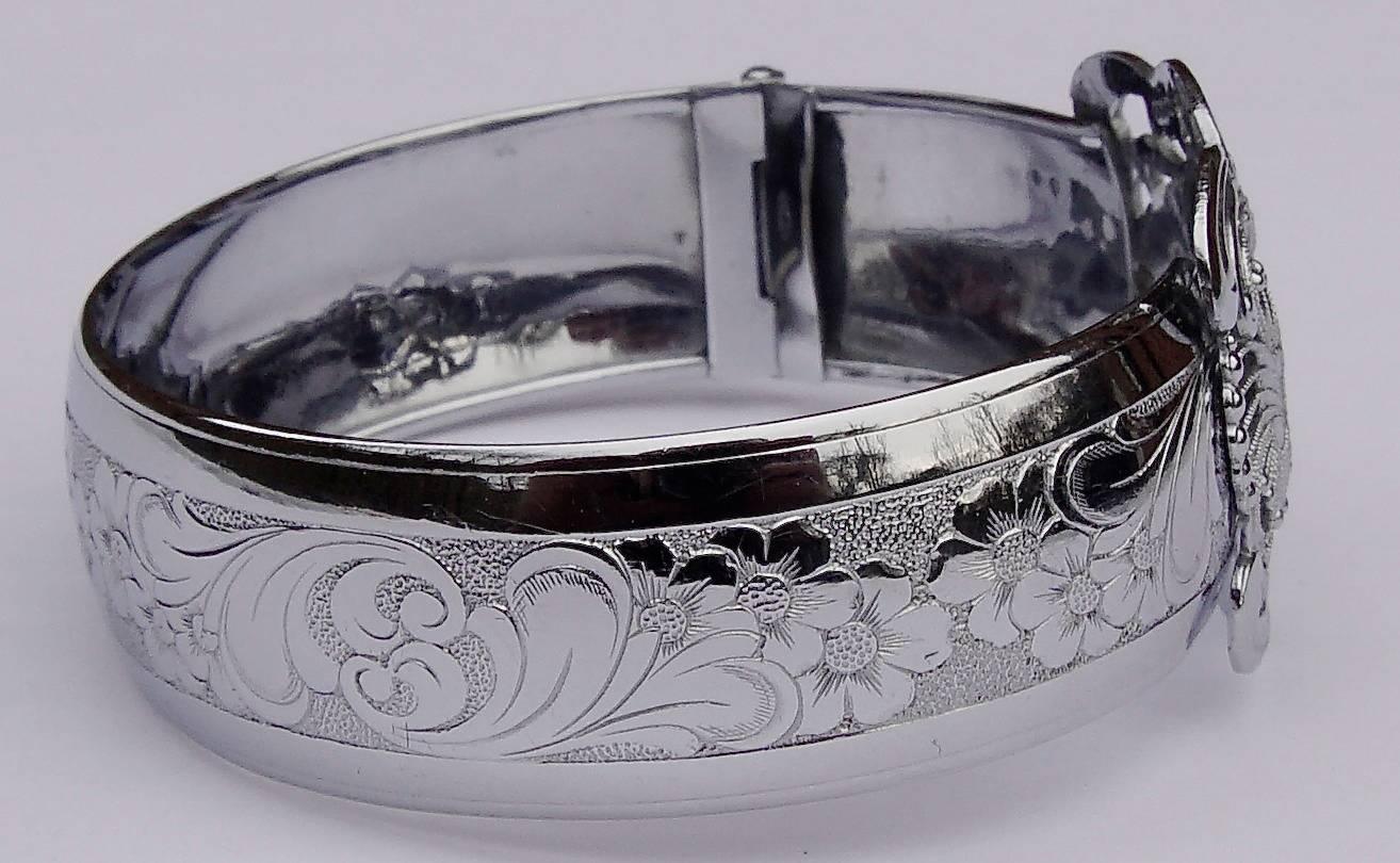 Shiny silver tone vintage bangle from the early twentieth century stamped AD, featuring a beautiful filigree and floral design centrepiece. The band width is 1.6cm / .63 inches, and the inner circumference measures 18.4cm / 7.24 inches. It has