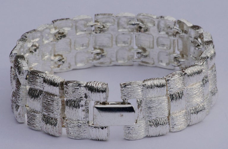 Napier elegant silver tone bracelet with textured weave design links. Measuring length 19cm / 7.5 inches by width 1.75cm / .69 inches. The brushed design gives a beautiful shimmering satin effect.

This is a stylish and quality vintage Napier