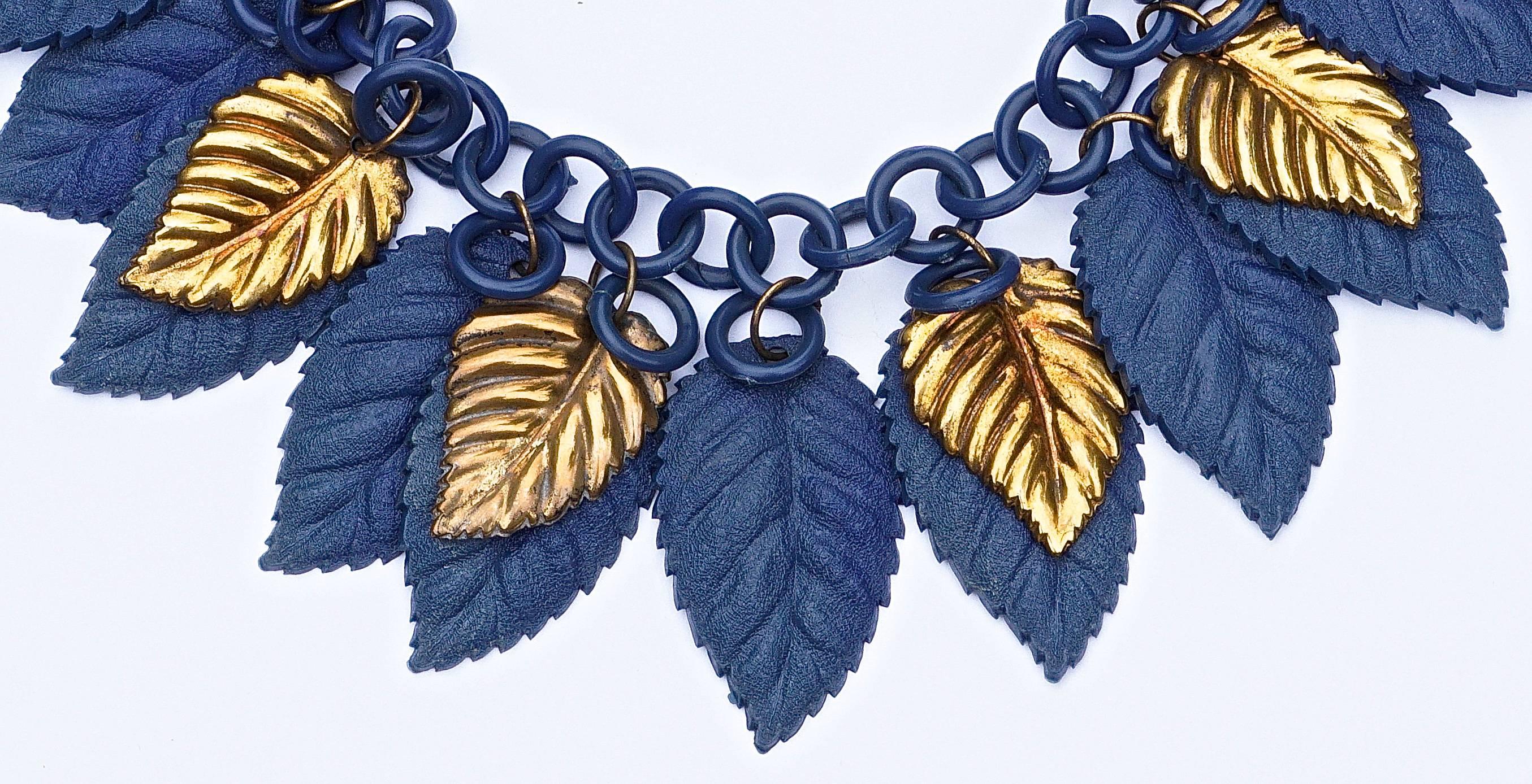 celluloid-Halskette aus den 1930er Jahren, mit dunkelblauen Kunststoff- und goldenen Metallblättern, die von der Gliederkette herabhängen.
Länge 40,5 cm, 15,94 Zoll. Die stilvollen Blätter messen eine Länge von 4,1 cm (1,6 Zoll) und 2,5 cm (0,98