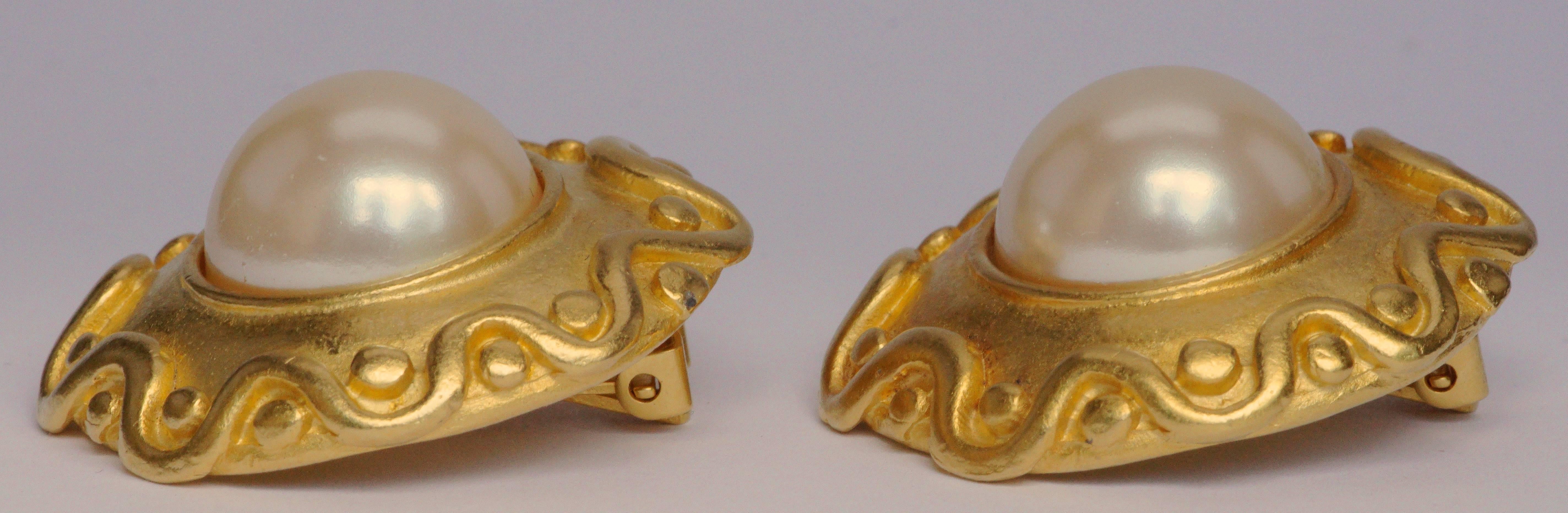 Kenneth Jay Lane round 1990s matt gold tone clip on earrings, featuring faux pearls and a wave design edge. Measuring diameter 3.2cm / 1.26 inches. The reverse is stamped Kenneth©Lane. They have a lovely golden glow.

This is a stylish pair of