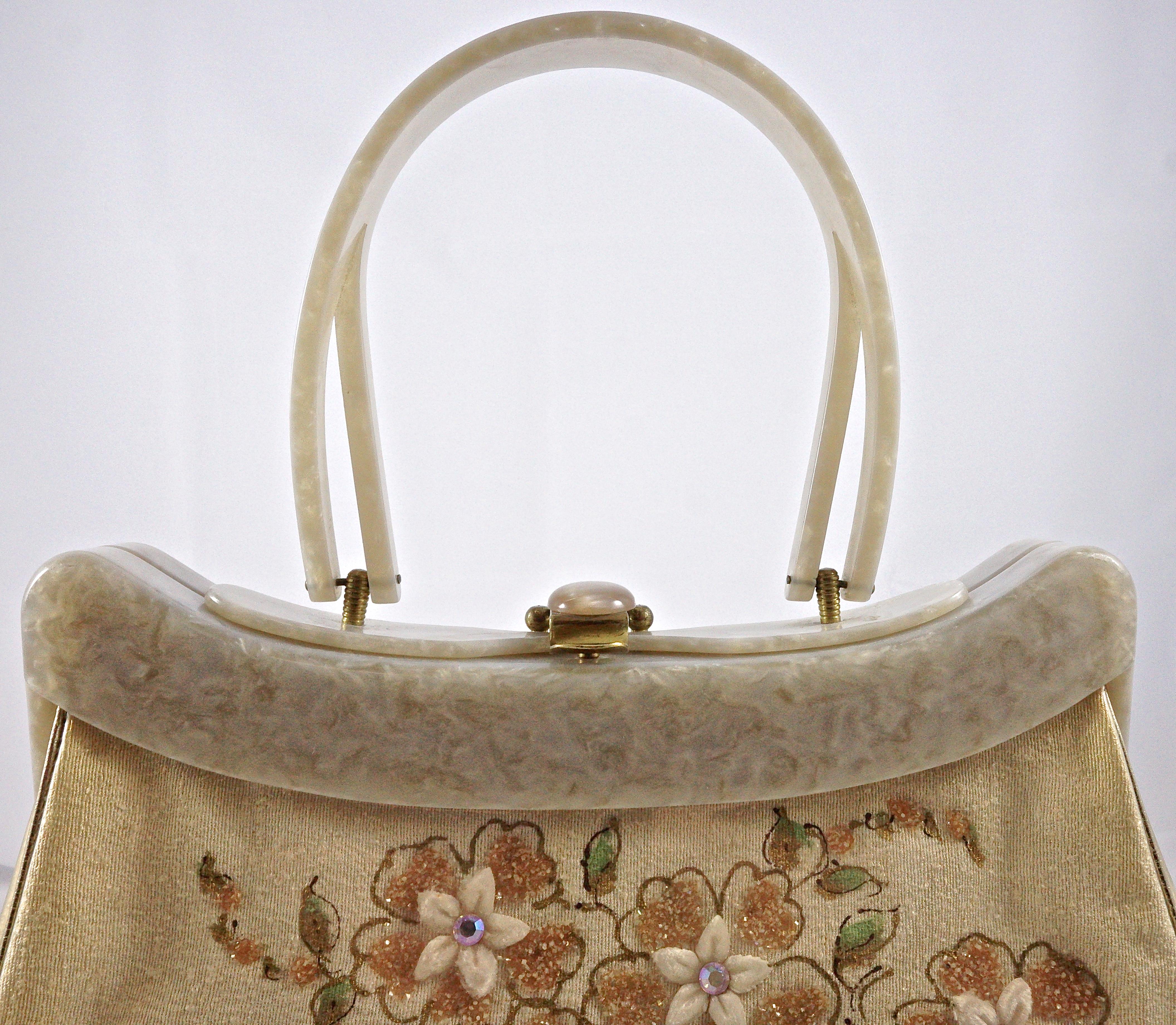 
Fabulous Rialto vinyl covered cream fabric handbag with gold tone metal fittings, and featuring painted flowers,  glittering embellishment, velvet and aurora borealis rhinestones to the front. The back is plain.  The edges are finished with gold