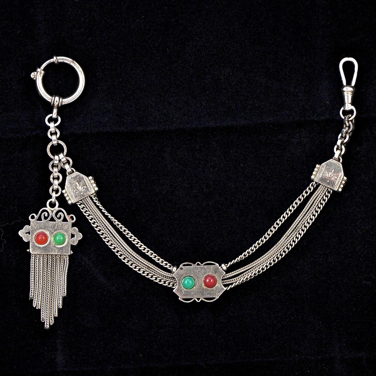 German Oberstein antique silver tone detailed pocket watch chain, featuring red and green stones. Measuring length 27cm / 10.6 inches. The watch chain is in very good condition, with scratching as expected.

This is a stylish and ornate pocket watch