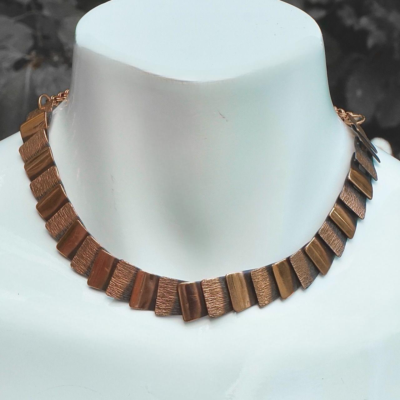 Conjunto de collar, pulsera y pendientes de cadena de eslabones de cobre anodizado de mediados de siglo, con un sencillo diseño texturizado y pulido.

El collar tiene un cierre de gancho ajustable. Mide 41,7 cm de largo por 1,4 cm de ancho.

La