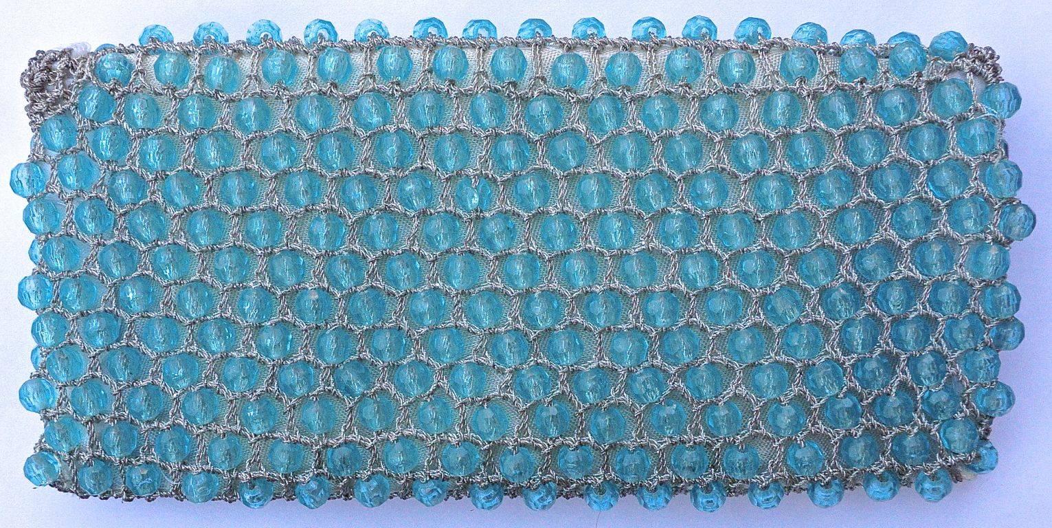 Blue faceted plastic bead clutch bag with silver crochet trim, fully lined in off-white satin, and in very good condition. Measuring 22cm (8.7 inches) by 10.7cm (4.2 inches). The lining is very clean, and has a pocket which has a label - Made in