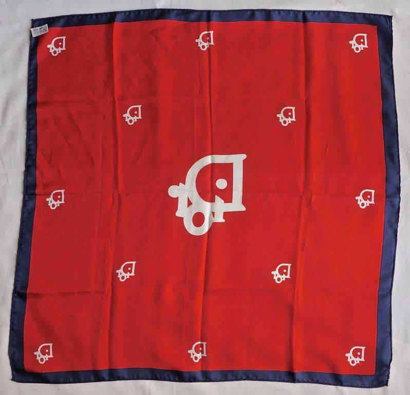 Red silk scarf by Christian Dior with a navy blue border and white signature logo. It has hand rolled edges, and is made in Italy. Measuring 66cm x 66cm, or 26 inches x 26 inches. There is a small stain towards the border.

This is a lovely classic