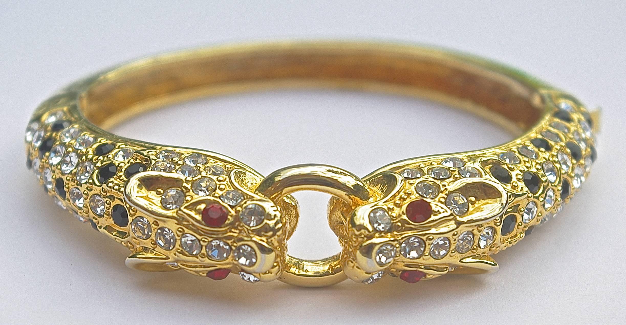 Gold plated leopard bangle featuring black and clear rhinestones and ruby red eyes. Measuring approximately width 6.7cm / 2.64 inches.  Circa 1980s.

This fabulous vintage statement bangle bracelet would bring style and glamour to any outfit.