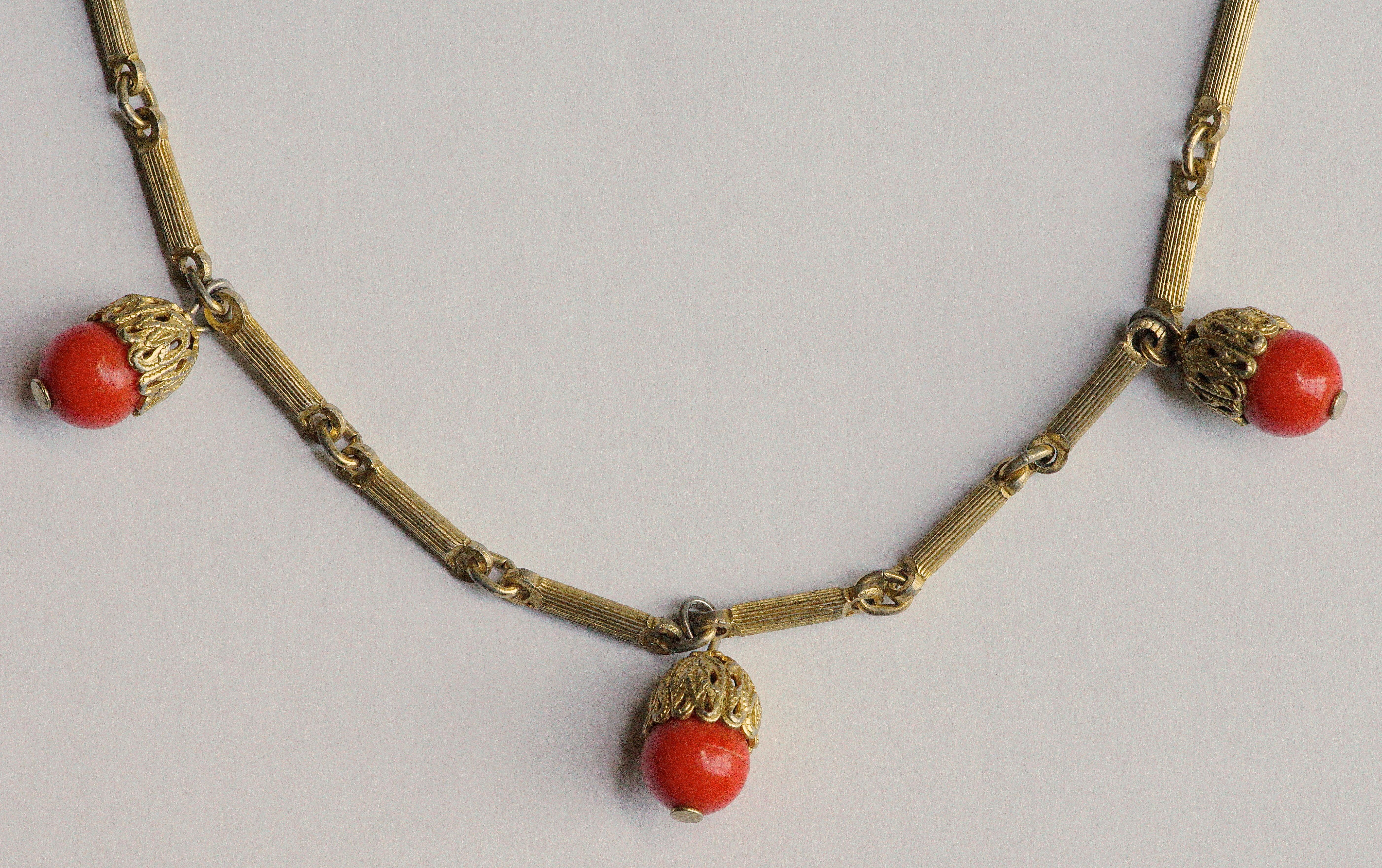 Long gold tone necklace with ridged detail links, and featuring fine filigree metal work set with faux coral stones. Length 123cm / 48.42 inches, and the faux coral stones are 7.5mm / .29 inch diameter. There is one stone missing close to the clasp.