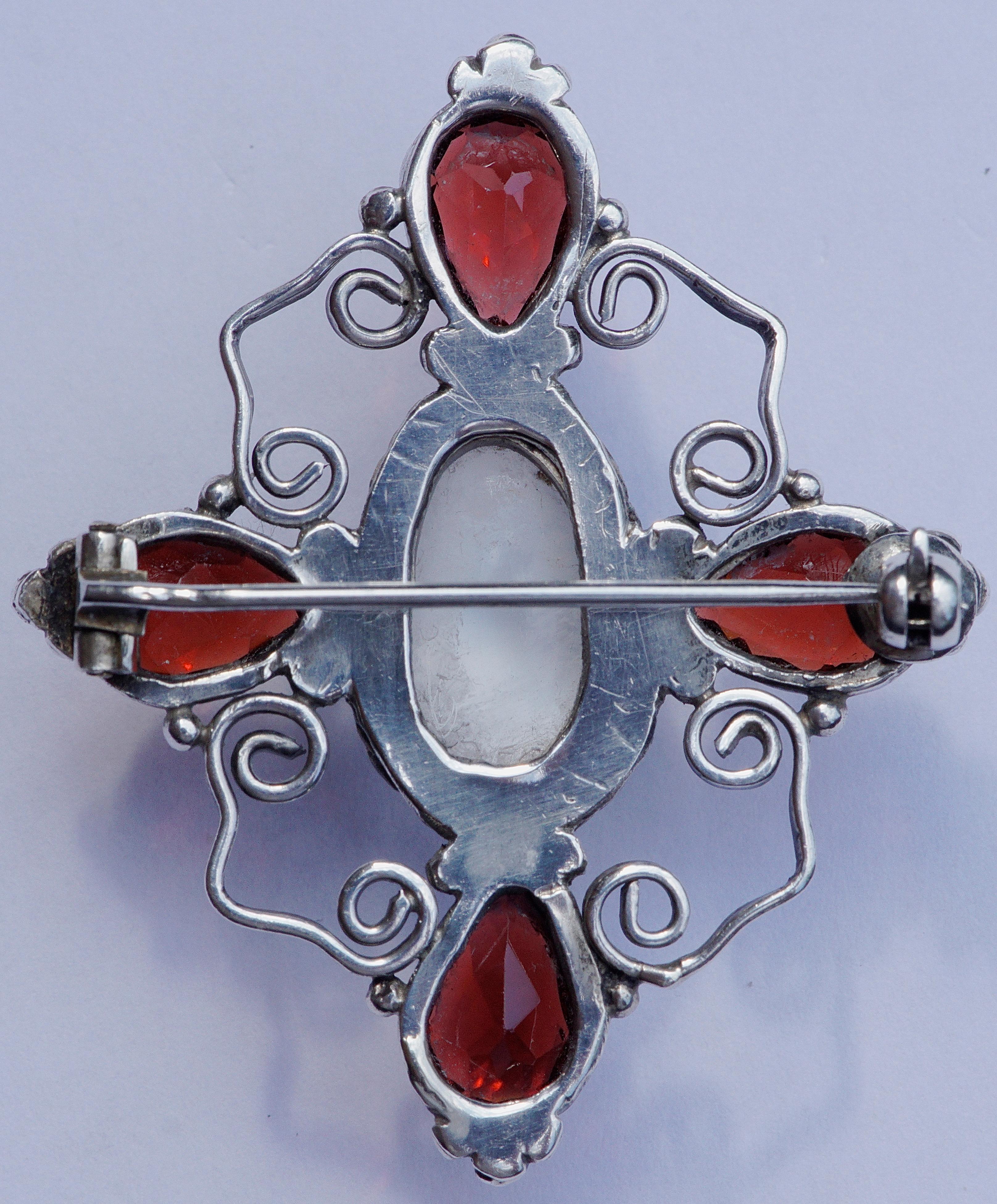 Beautiful rope twist and swirl design silver brooch featuring four faceted faux garnets, and a faux moonstone. The brooch measures 4.5cm / 1.77 inches by 3.8cm / 1.49 inches. There are no hallmarks, but the brooch tests as silver. The pin is bent at