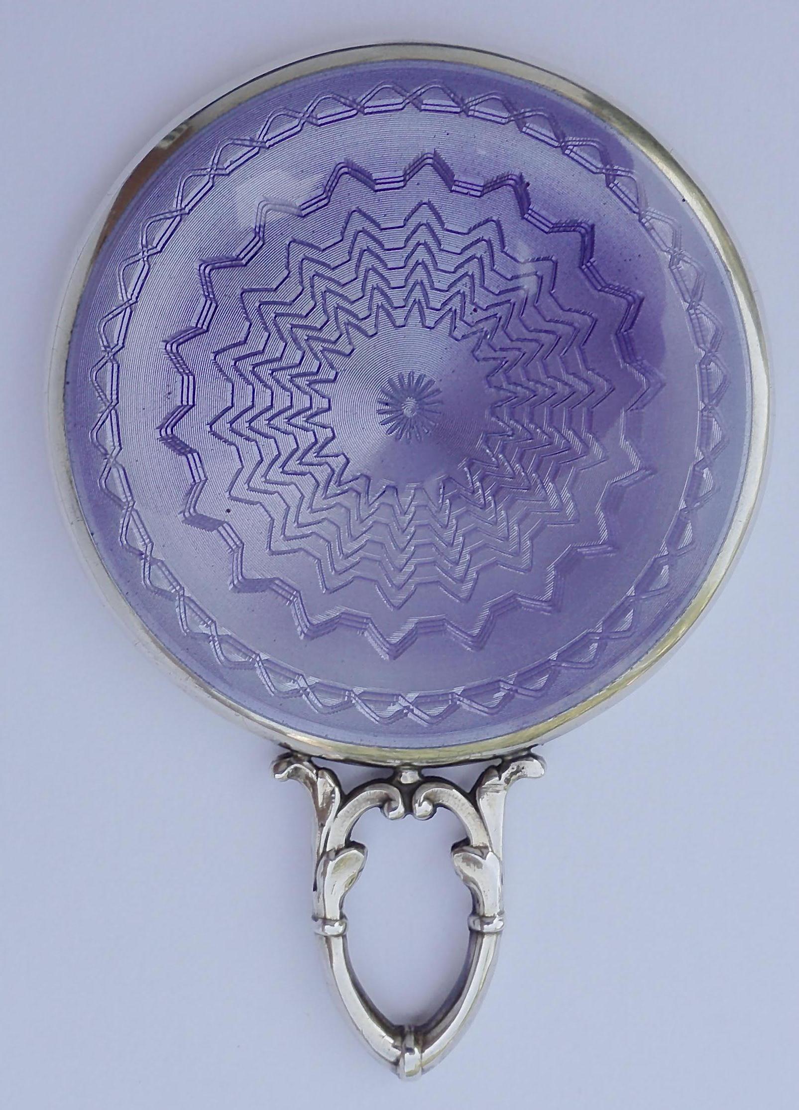 Art Deco sterling silver comb and mirror featuring lilac enamel guilloché work. The comb and mirror fit in the original purple leather case, which is fully lined and has separate compartments for the mirror and comb. The case closes with a metal