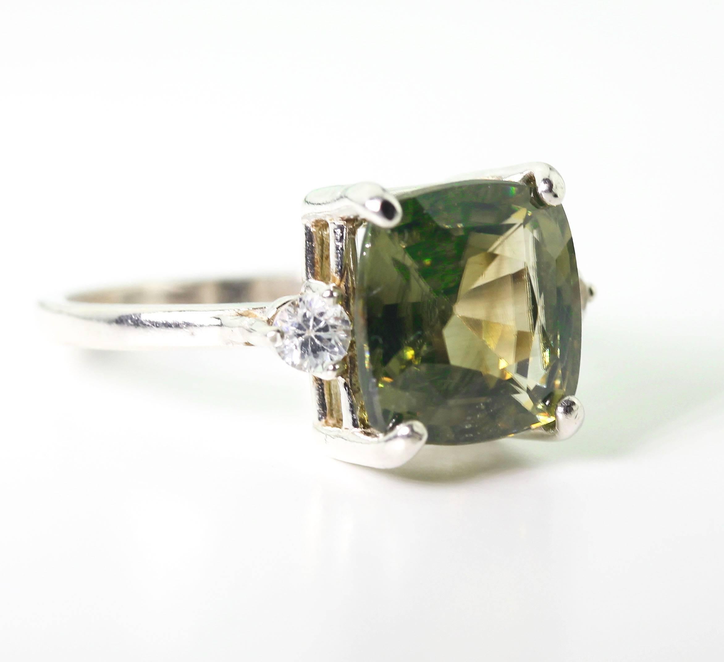 This glittering beautiful Green Spinel is 6.7 carats and is enhanced with two (1 carat) brilliant white Cambodian Zircons set in a sterling silver ring size 7.  The ring is sizable.    More from this seller by putting gemjunky into 1stdibs search