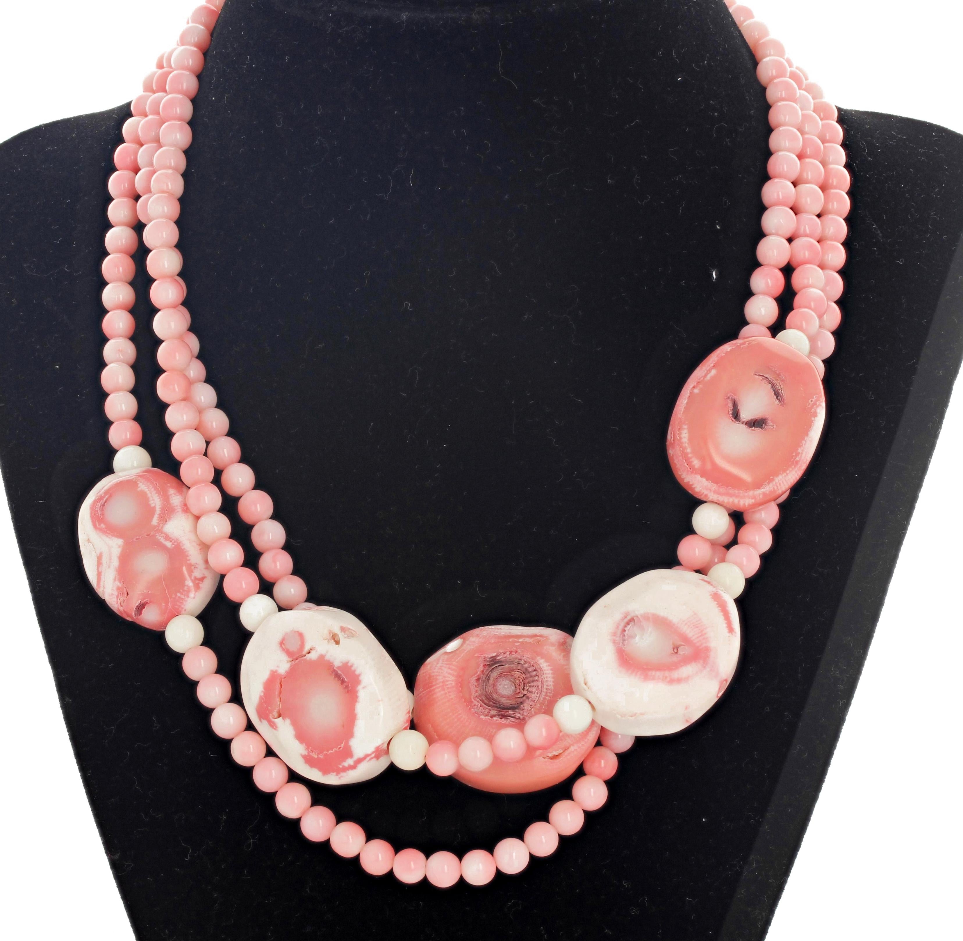 Triple strand of pink and pinky white Coral with silver tone clasp.   The smaller round Coral are 6 mm and the large ones are approximately 30 mm x 23 mm and the necklace is 17 inches long. 
