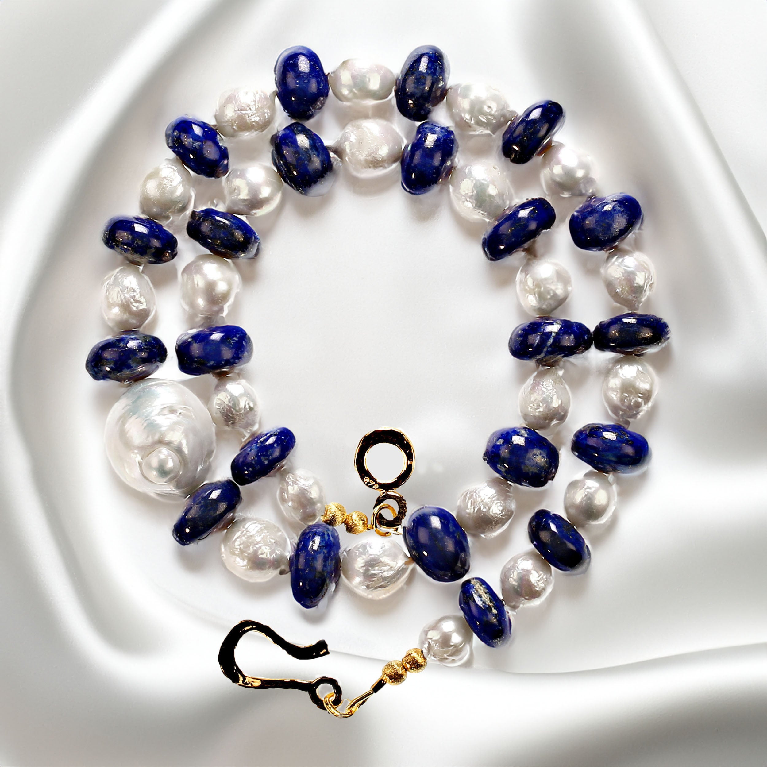 20 Inch stunning lapis lazuli and white pearl necklace.  The lapis is smooth and fashioned in thick rondelles, and just slightly graduated.  The central pearl focal is absolutely gorgeous.  It is 20x18mm and flashes pinks and greens. The necklace is