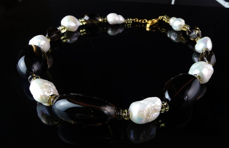 Necklace of iridescent white Pearls mixed with various sizes of Smoky Quartz. These Pearls are freeform and 18-22 mm in size. There are three large puffy Smoky Quartz nuggets, four softly faceted transparant Smokies, and lots of sparkling