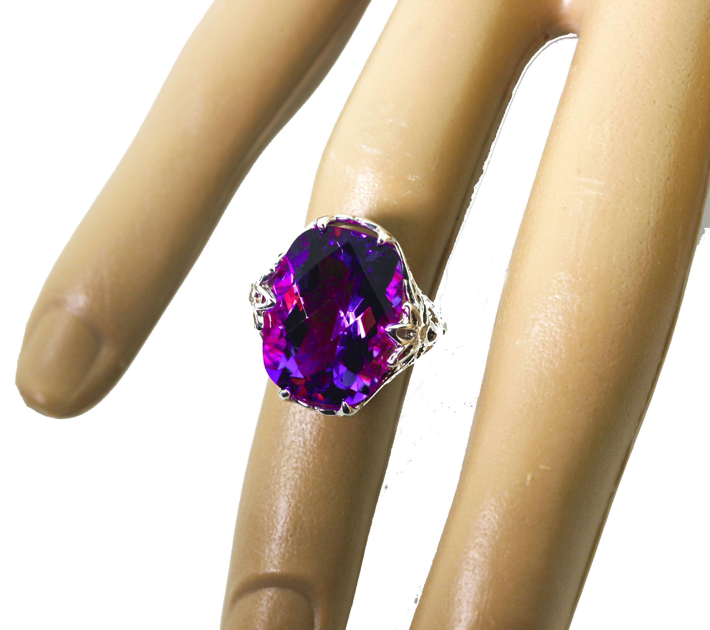 Glittering checkerboard gemcut natural 9.5 carat Amethyst (16.5 mm x 12.5 mm) with natural pinky flashes inside the stone.  It is set in a sterling silver ring size 5 (sizable FOR FREE).   