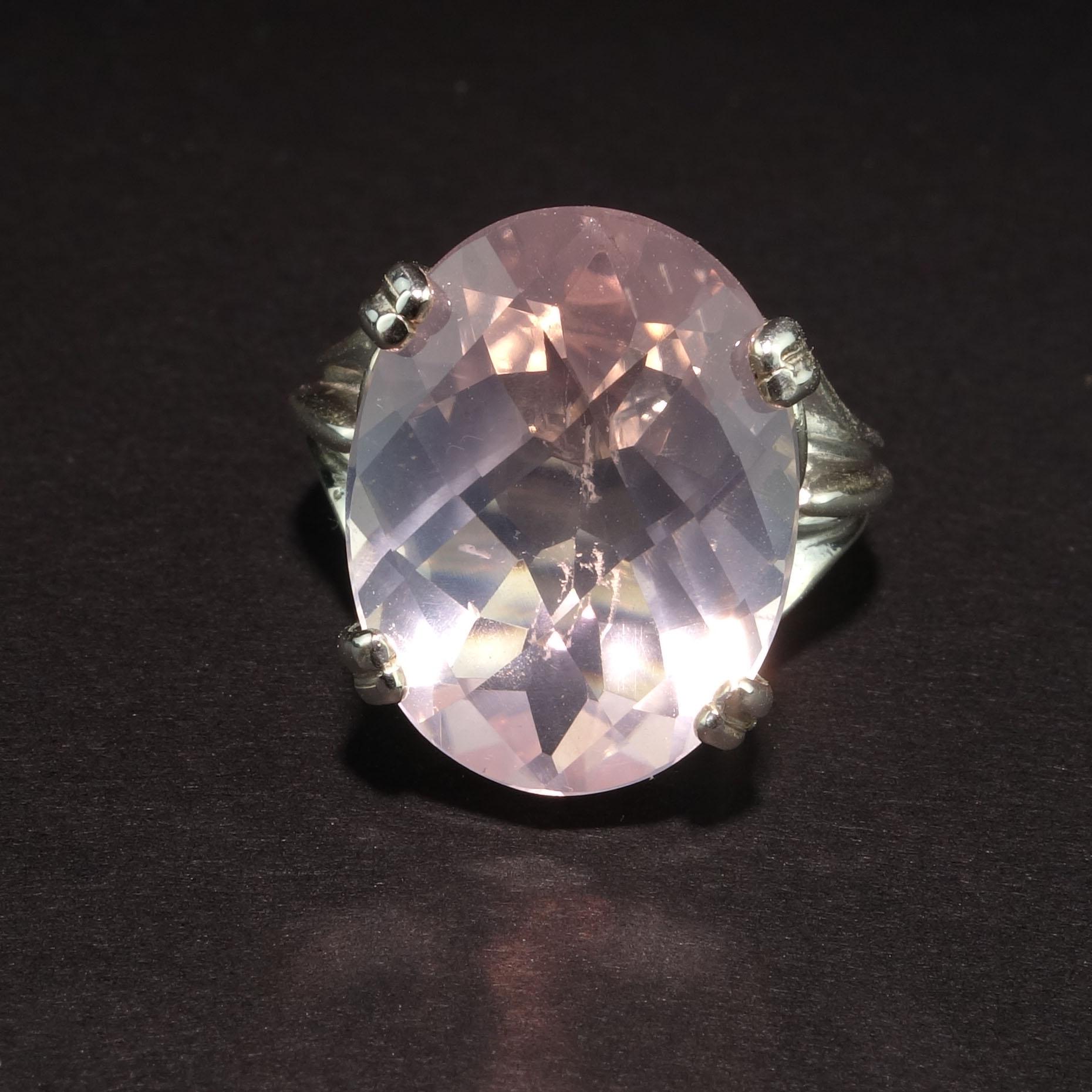 Custom made, sparkling oval Rose Quartz set in detailed Sterling Silver ring.  This unique Rose Quartz has flashes of mauve and a checkerboard table.    It is 17x13mm and is 10.81 carats.  Size 7.  No changes in Auction Sale.

