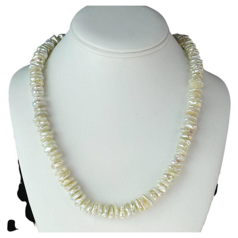 Iridescent, Center Drilled, approx. 10mm Coin Pearl Necklace. The Freshwater Pearls flash pink, yellow, and blue. Tiny, faceted Silver Topaz beads randomly accent the 21.5 inch pearl strand. The Clasp is a freshwater pearl finished with Sterling