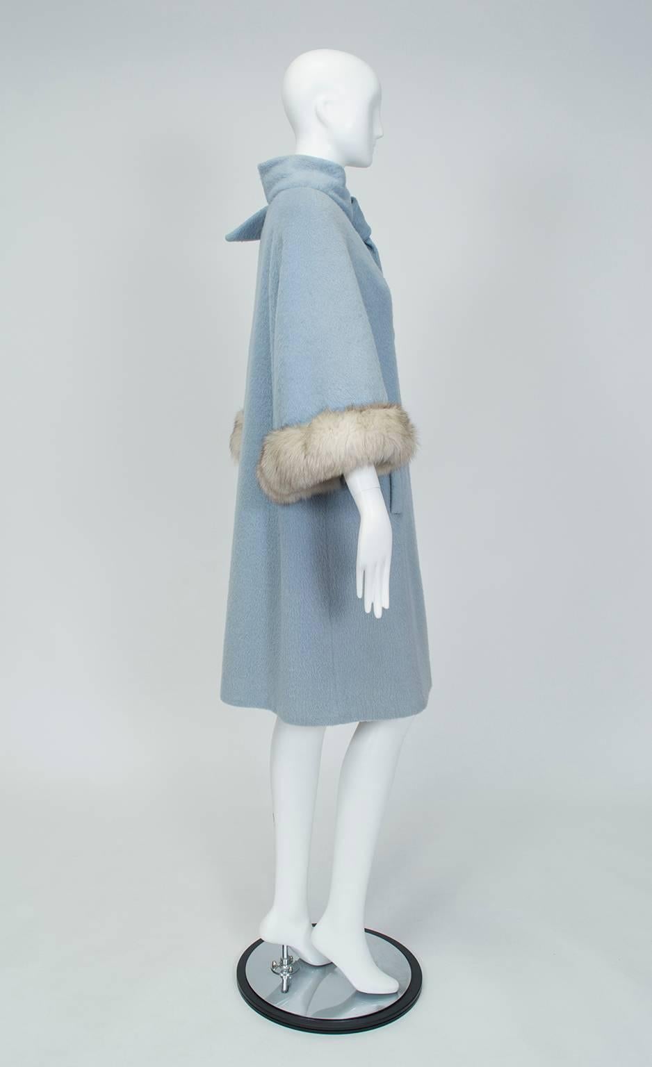 Sometimes a gentle reminder of blue sky is all it takes to get through a dreary winter. With its ideal hue and ingenious design, this coat is up to the task: fully-functional coat sleeves are concealed by a fluttering cape trimmed in silver fox fur.