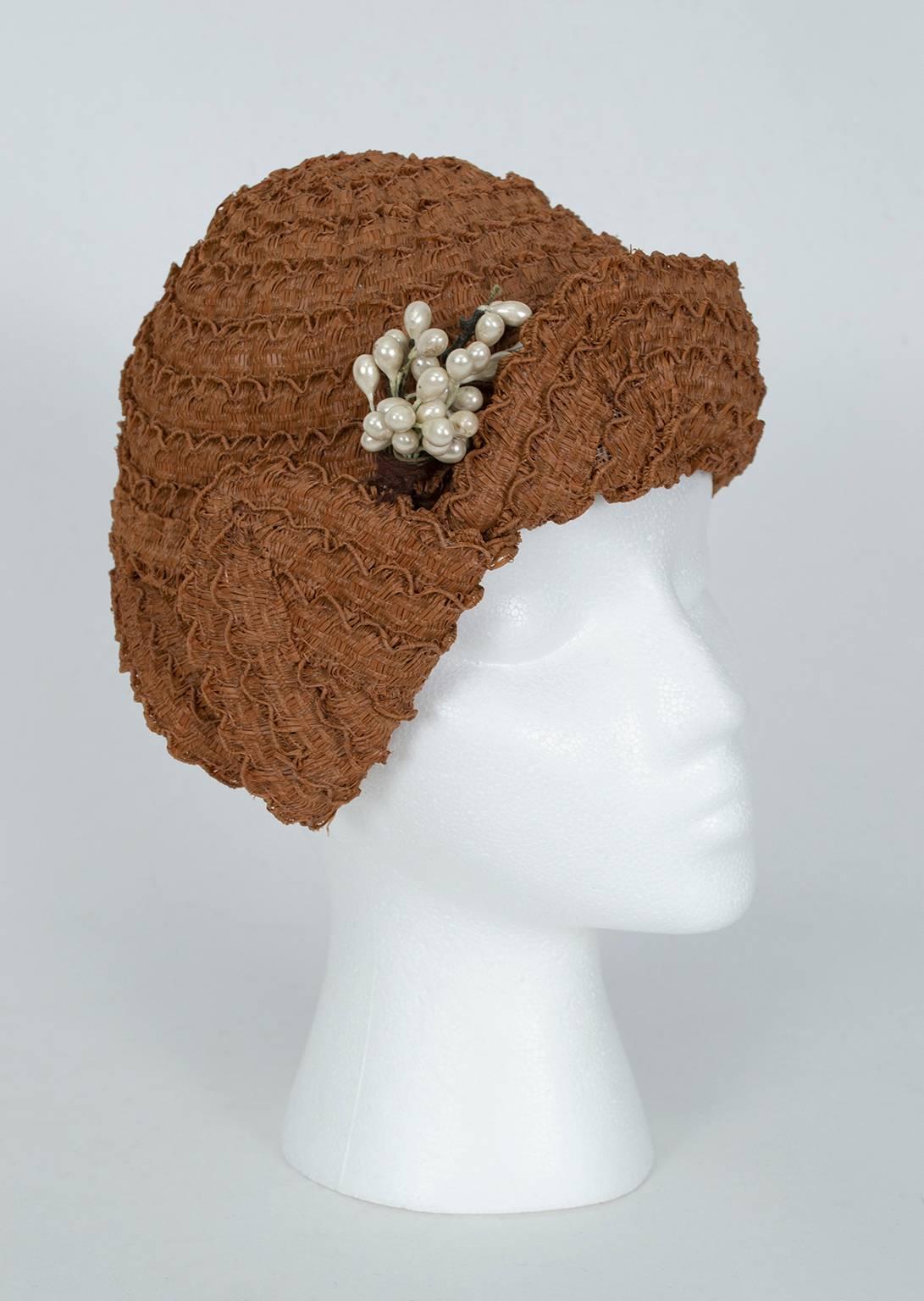 No ordinary cloche, this hat's charm lay in its asymmetrical geometry, which covers the right ear but exposes the left. A perfect foil for the angular drop waist dresses of the Jazz Age.

Scalloped straw cloche with upturned front brim and