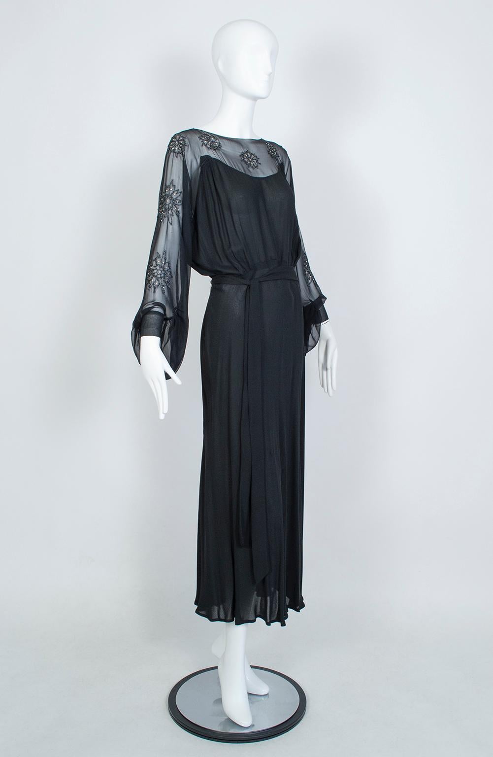 Quite possibly one of the most alluring gowns we’ve ever seen despite its full coverage, blouson cut and long sleeves. Solid from bust to hem, the upper chest, upper back and enormous bellows sleeves are transparent except for 15 glass bead and
