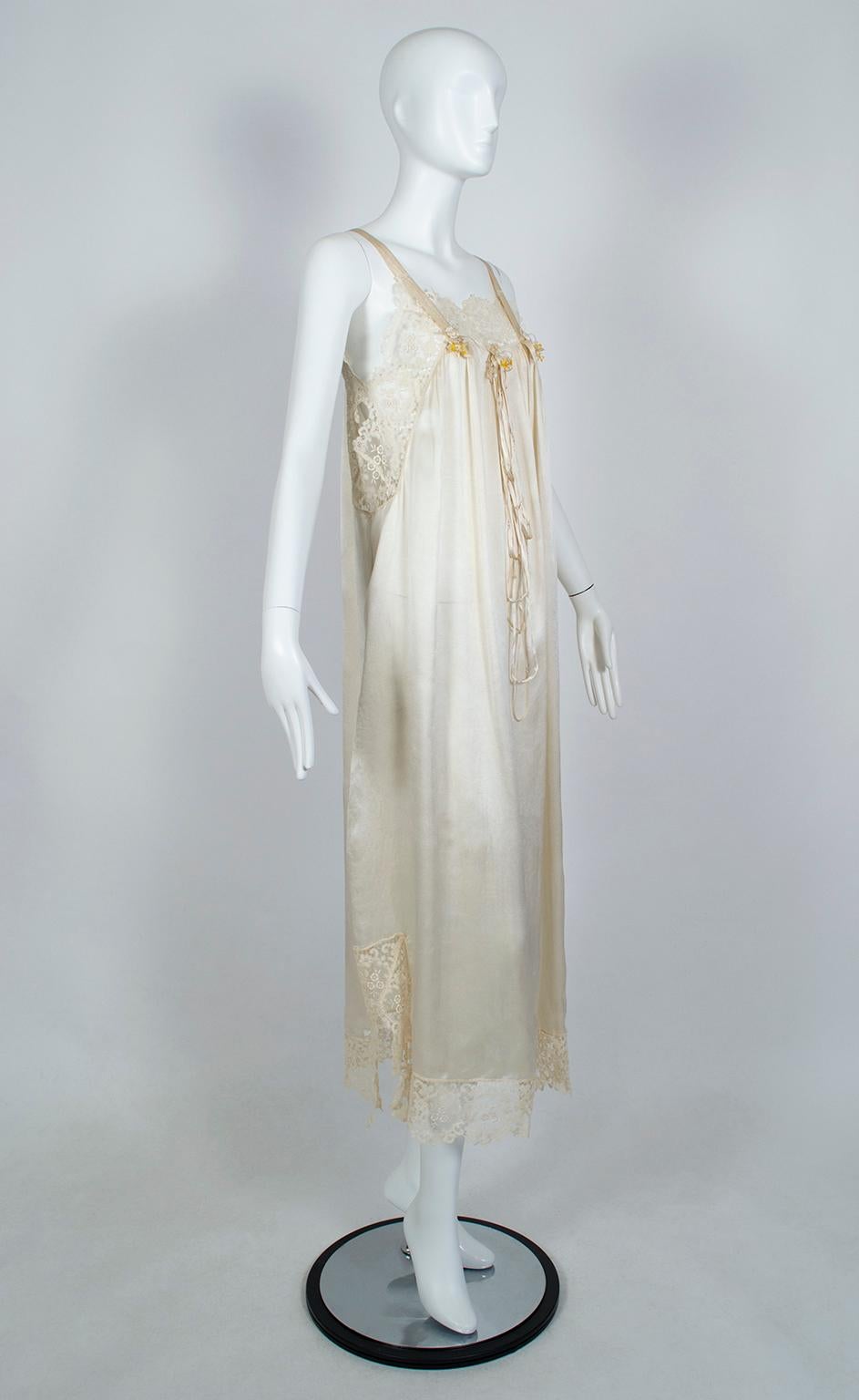 Part of a spectacular wedding trousseau, this gown is covered in 3 ½” swaths of French lace around the neckline and hem, and down each side from the shoulders to the waist. Elegant and feminine, it also features unusual cutouts at the underarms and