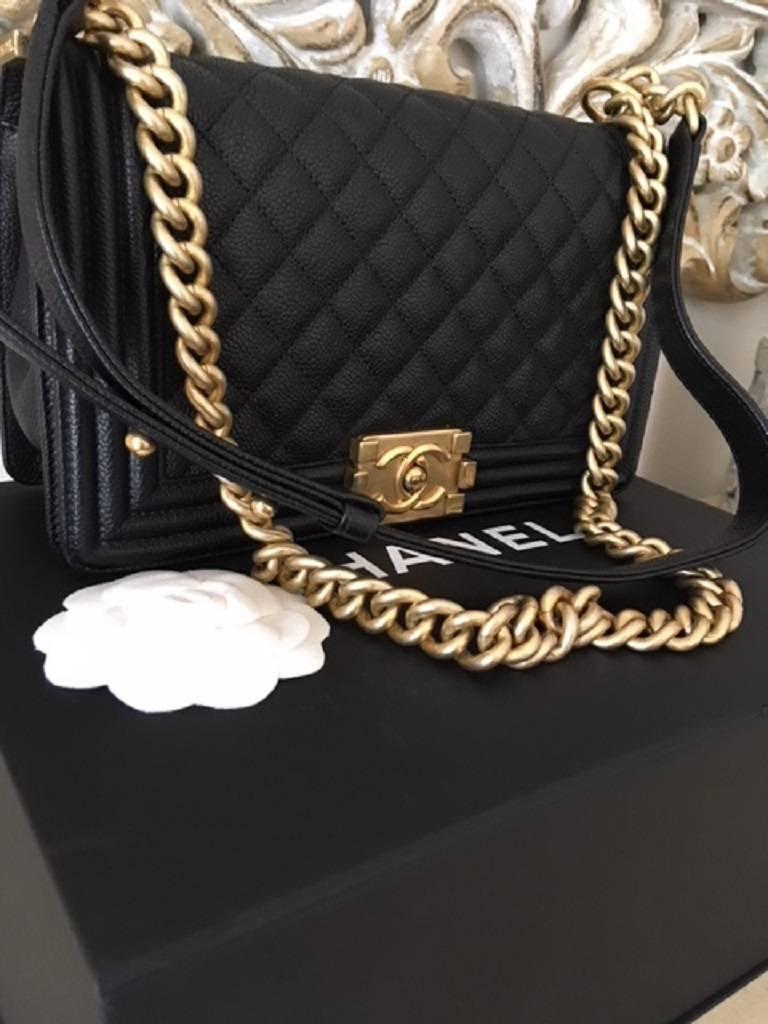 This Chanel Boy Bag has the internal green/ olive leather interior with one open pocket. The bag is the medium size with the quilted caviar leather and gold chain hardware. The hardware can be worn as a single or as a double. The bag is 100%