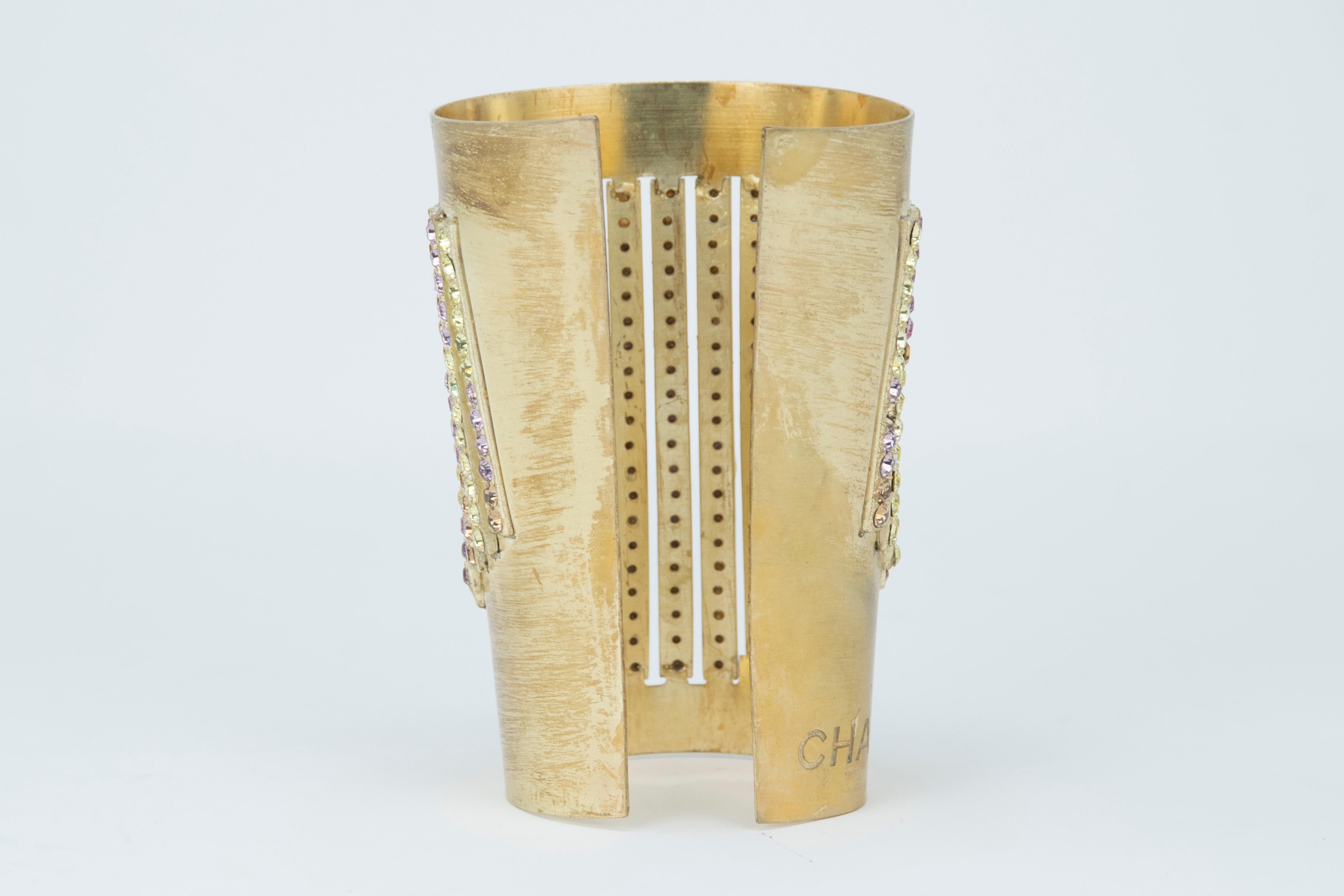 This Chanel cuff makes for an incredible statement piece.  Gold with rows of consecutive multicolored rhinestones.  Chanel engraved into the side of the gold.  Perfect for a more dressed up look or to pair with a button down and jeans.

Condition: