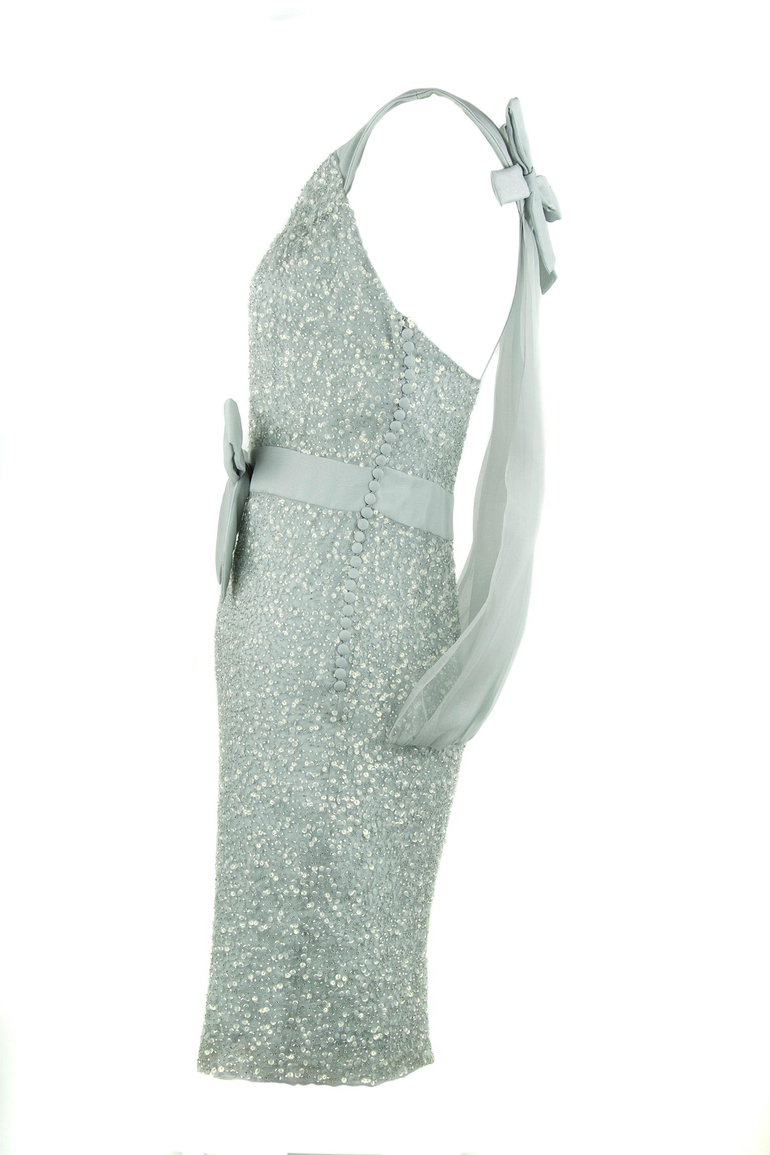 Incredible Christian Dior piece, the epitome of classic and sophisticated with a element of glamour.  Gray with a slight tint of light blue, this dress is adorned in sequins.  A beautiful organza overlay on the back of the dress with an elegant bow