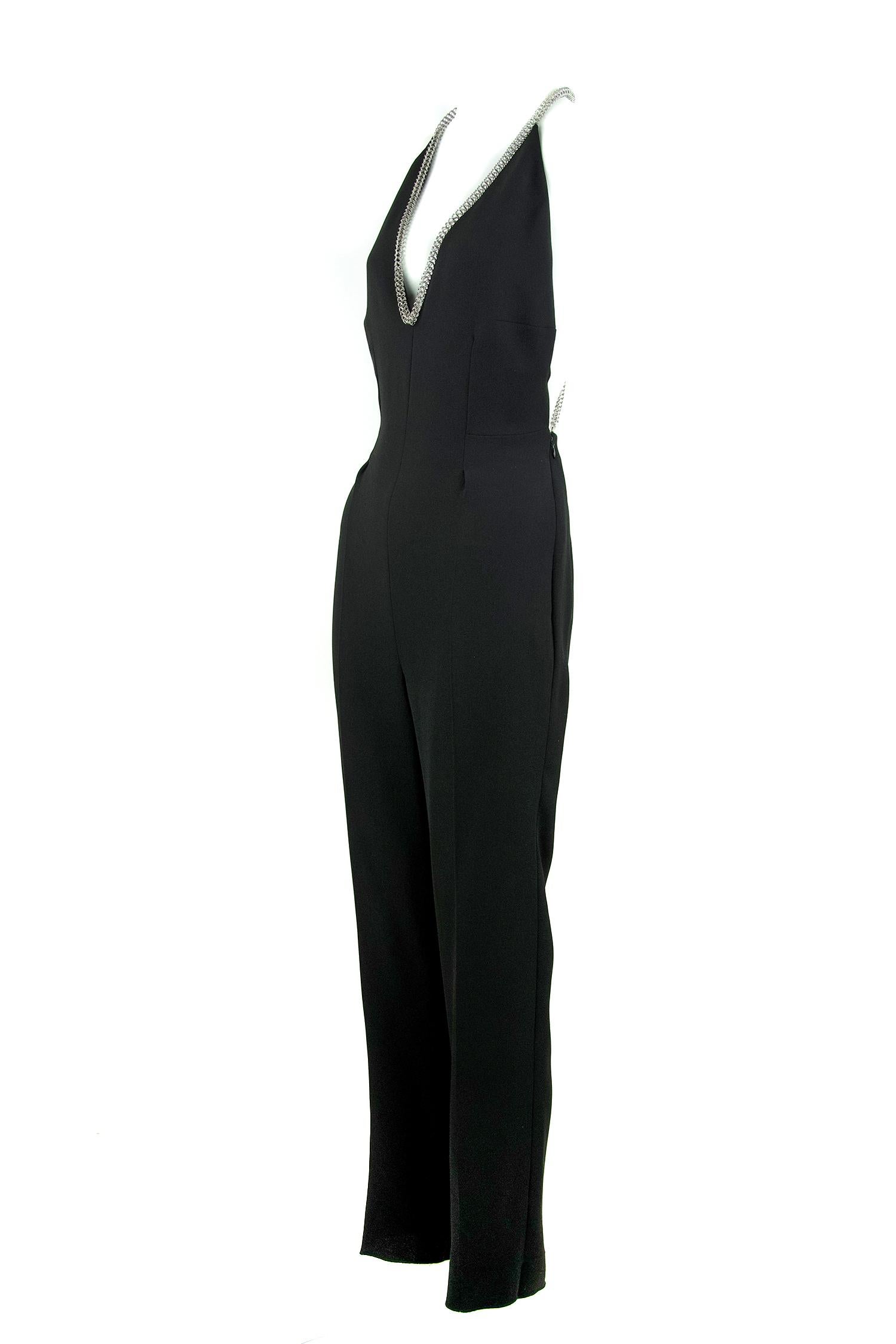 Classic YSL black jumpsuit with sexy open back and low v-neck in the front.  The top is finished with an silver chain, giving this piece a slightly edgy feel.

Size: FR 38

Condition: Pristine

Composition: 100% silk

Care: Dry clean only

Made in