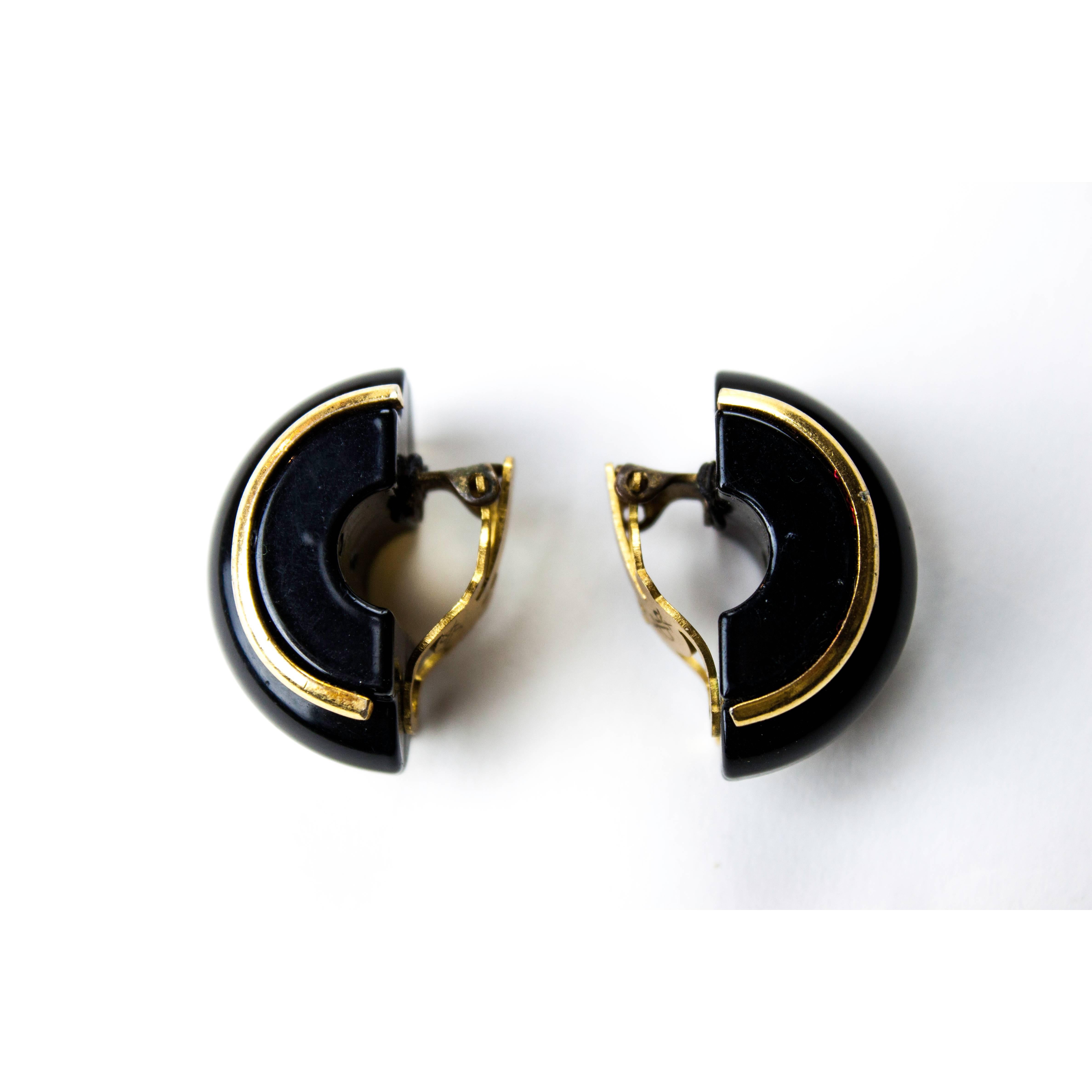 These half creole Yves Saint Laurent clip-on earrings are constructed from black  lucite mimicking lacquer material. These delicate crescents are adorned with gold lucite piping that emphasis the modern and exotic shape.
Signed on the metal plates