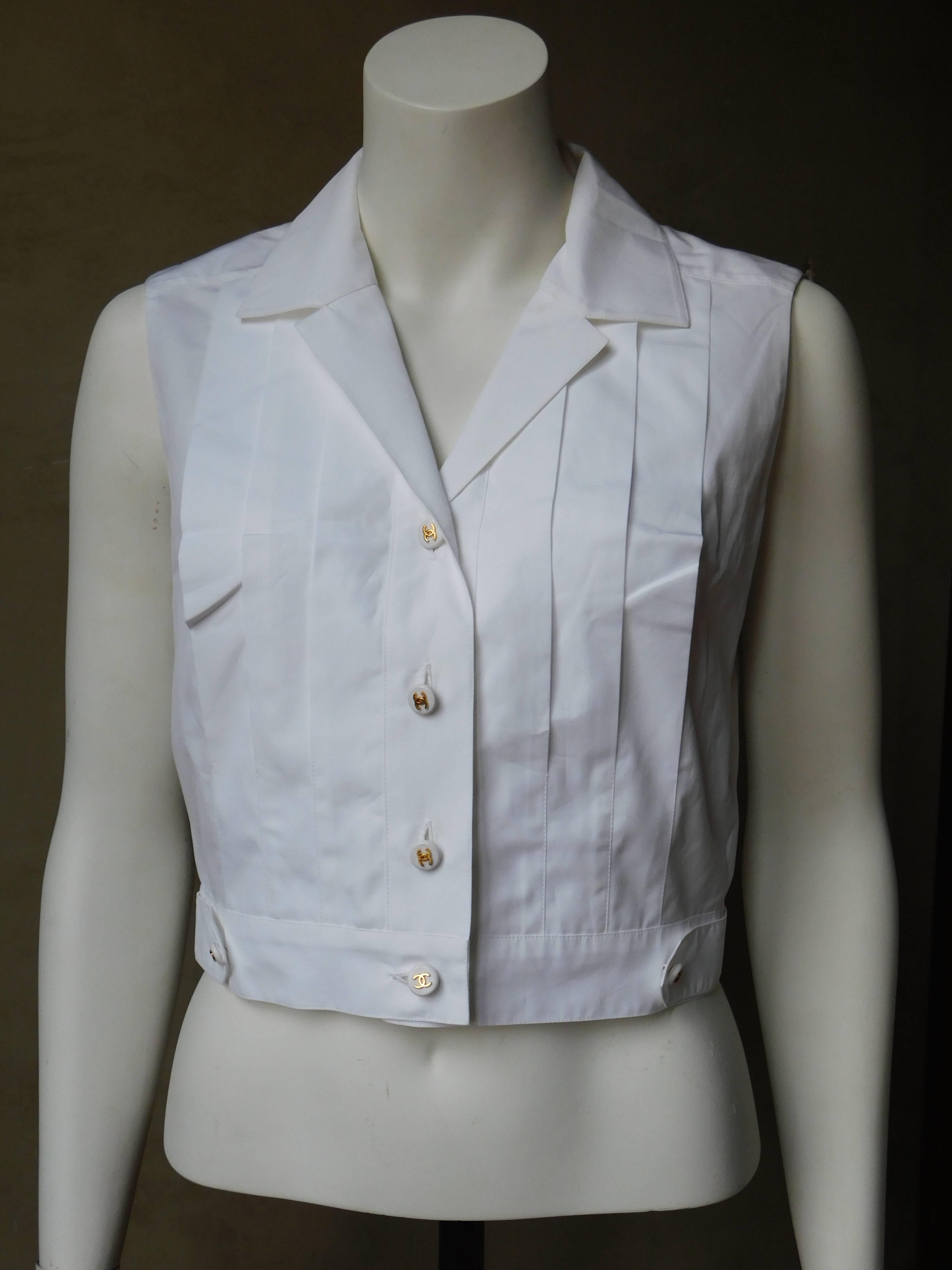 Crisp white cotton Chanel Boutique button front pleated sleeveless shirt. Chic slightly cropped fit with buttoned waist band. In very good condition.
Chanel Spring 1997 collection