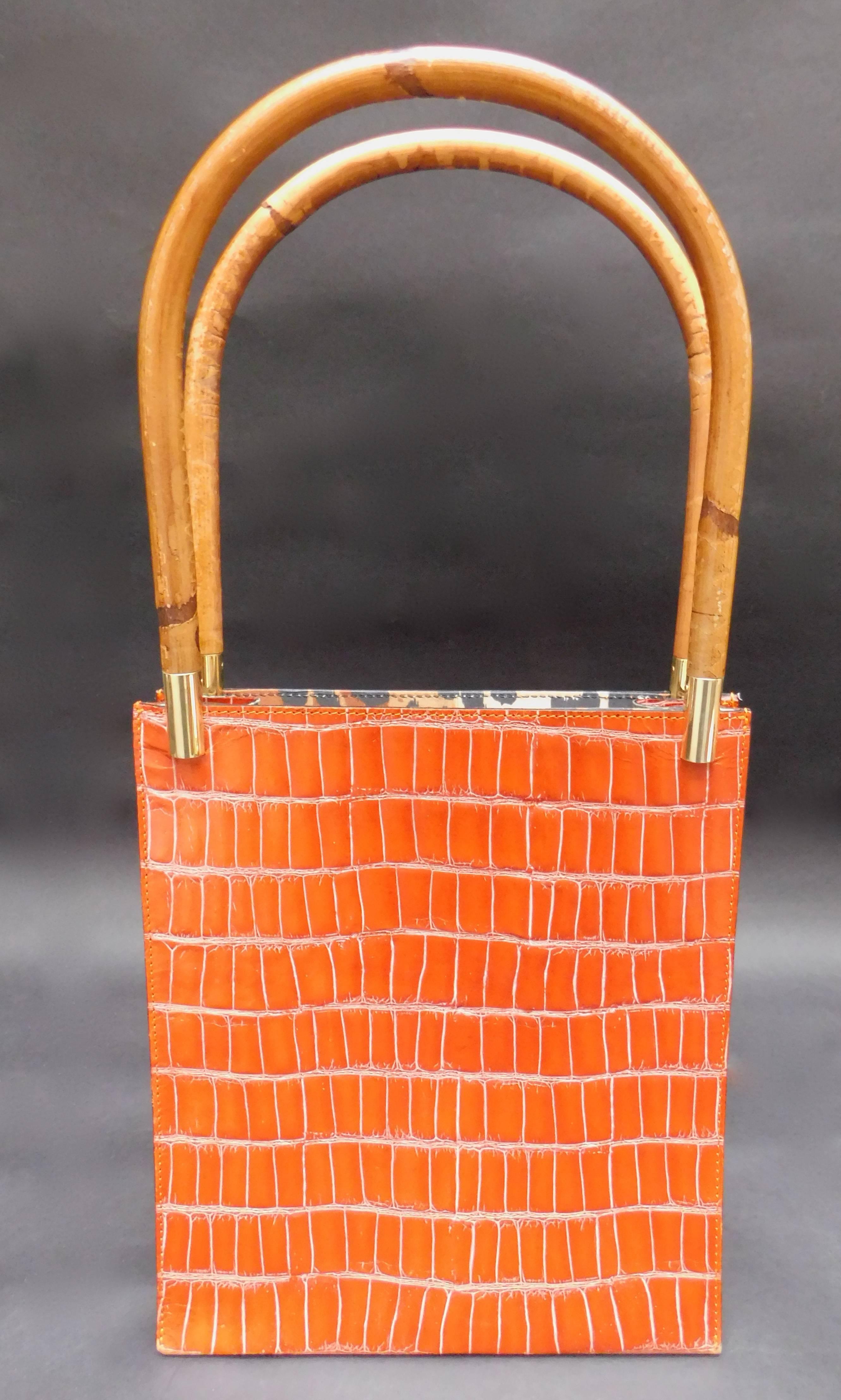 A 1980's Kenzo Orange embossed leather handbag with bamboo handles and gold accents. The interior is lined in leopard printed cotton with one zipper pocket and one leather open pocket. The handbag is in fantastic condition and the bamboo handles are