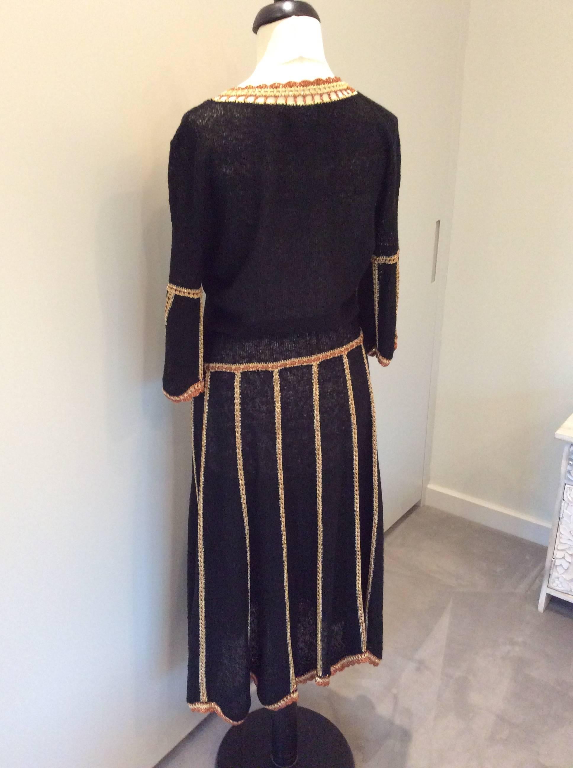  A 1970's Mary Ruane Black knit dress with copper and soft gold coloured metallic thread detail to neckline, bell sleeves, skirt and hemline.  Low, round neckline, 3/4 sleeves, dropped waist with tie belt and gently gored skirt creating scalloped
