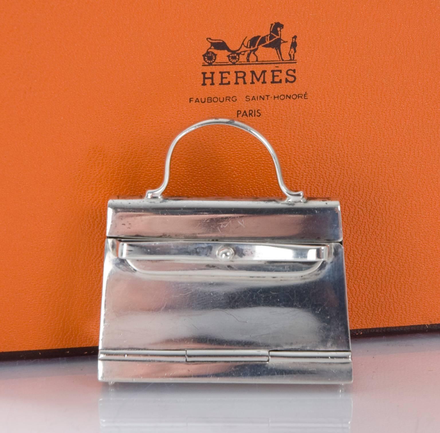HERMES Paris Pill Box in  925 Sterling Silver styled as a 'Kelly' Handbag.  Opens by pull towards front. Silver Stamp is located inside on the bottom.
No original packaging,but comes in a small Hermes box.
Some small scratches and marks and the