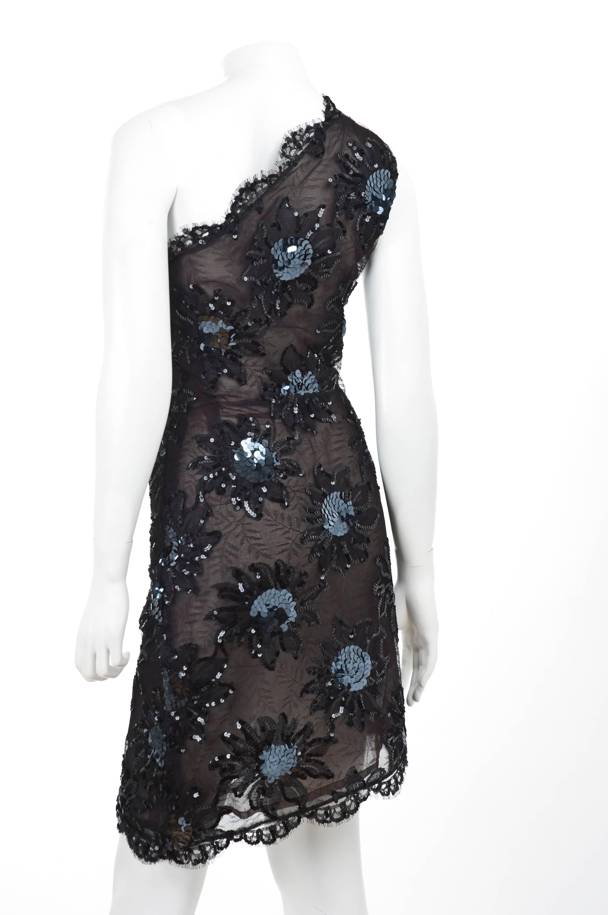 1987 Rare Yves Saint Laurent Cocktail Dress. Black lace with a leave pattern and two tone sequins applications.  
The Dress is semi sheer and has just at the right places the sequin applications. Asymmetrical hemline.
Brown sheer lining gives the