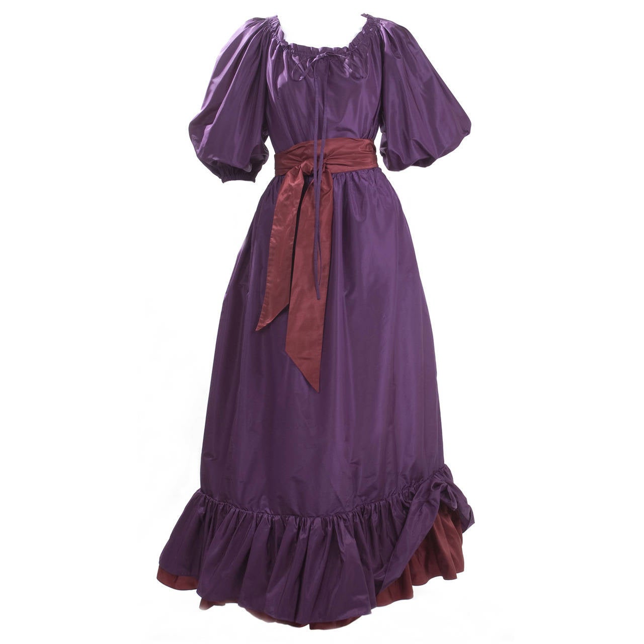 Yves Saint Laurent Taffeta Blouse, Skirt and Cape.
The blouse is solid purple and the skirt has a burgundy sash and the last ruffle is in the same color. The sash is attached to the skirt, pockets in the side seam.
The cape is a tone on tone play