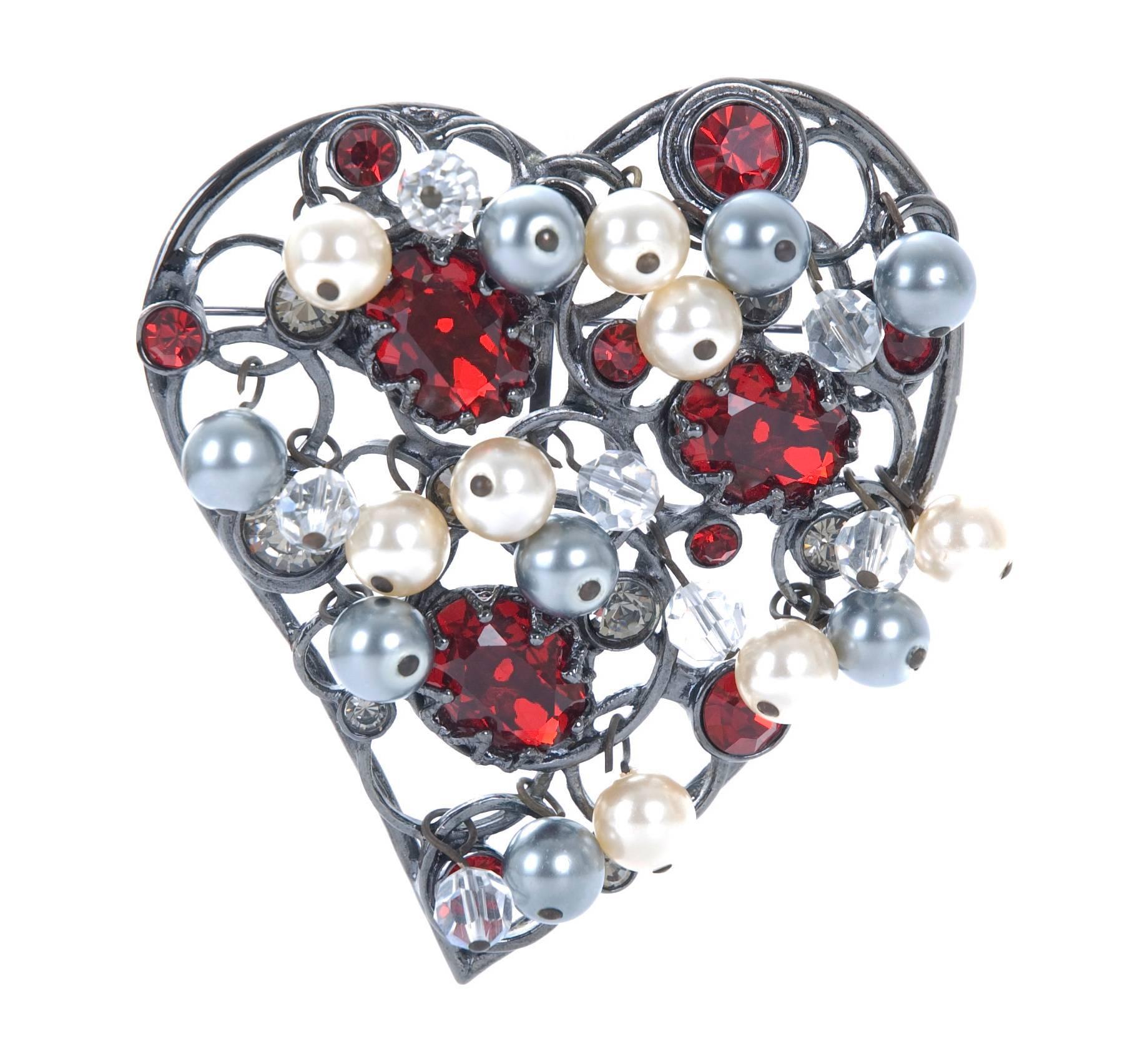 YVES SAINT LAURENT Heart Brooch-Pendant in shades of ruby glass diamonds glass with faux white and grey pearls. Design on antique dark silver finish. There is a loop in back for a chain as well.
First Heart Brooch shown 1961, then re-edited in