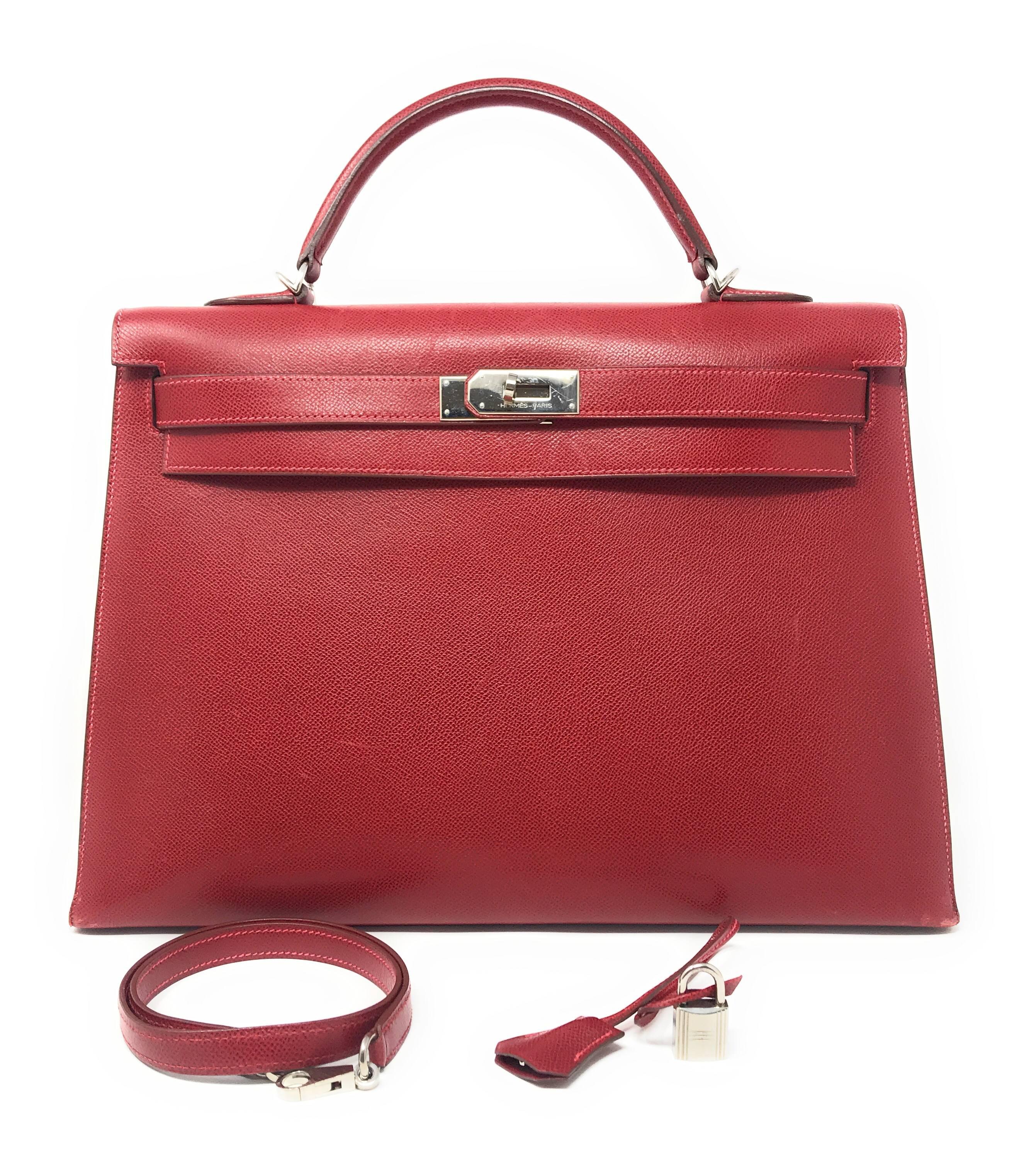 This Hermes Kelly bag is crafted in red Buffalo leather which is relatively water resistant. 
It is the structured Sellier style accented with Palladium hardware. This bag has the versatility of being worn as a shoulder bag since it has a detachable